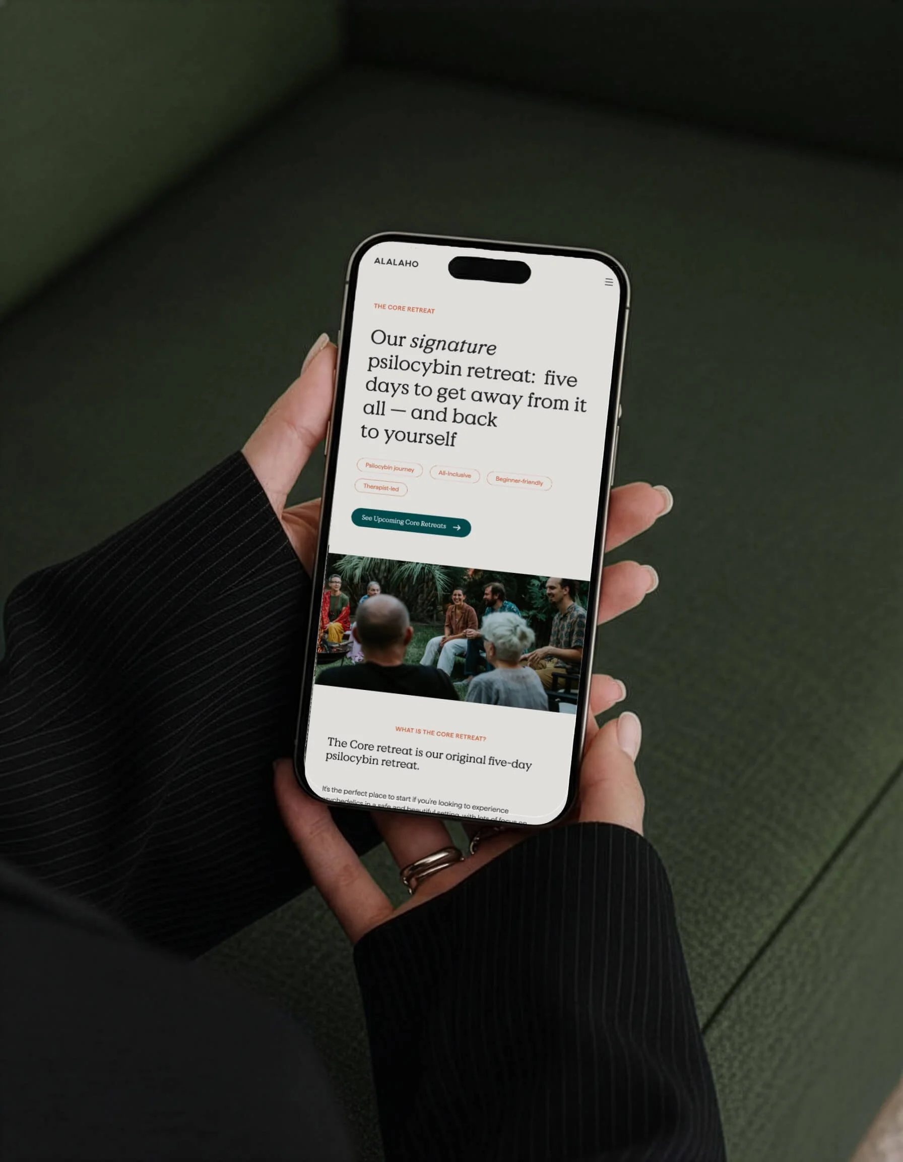 Person holding a smartphone displaying a webpage about a psilocybin retreat, with a group photo visible on the lower part of the screen.