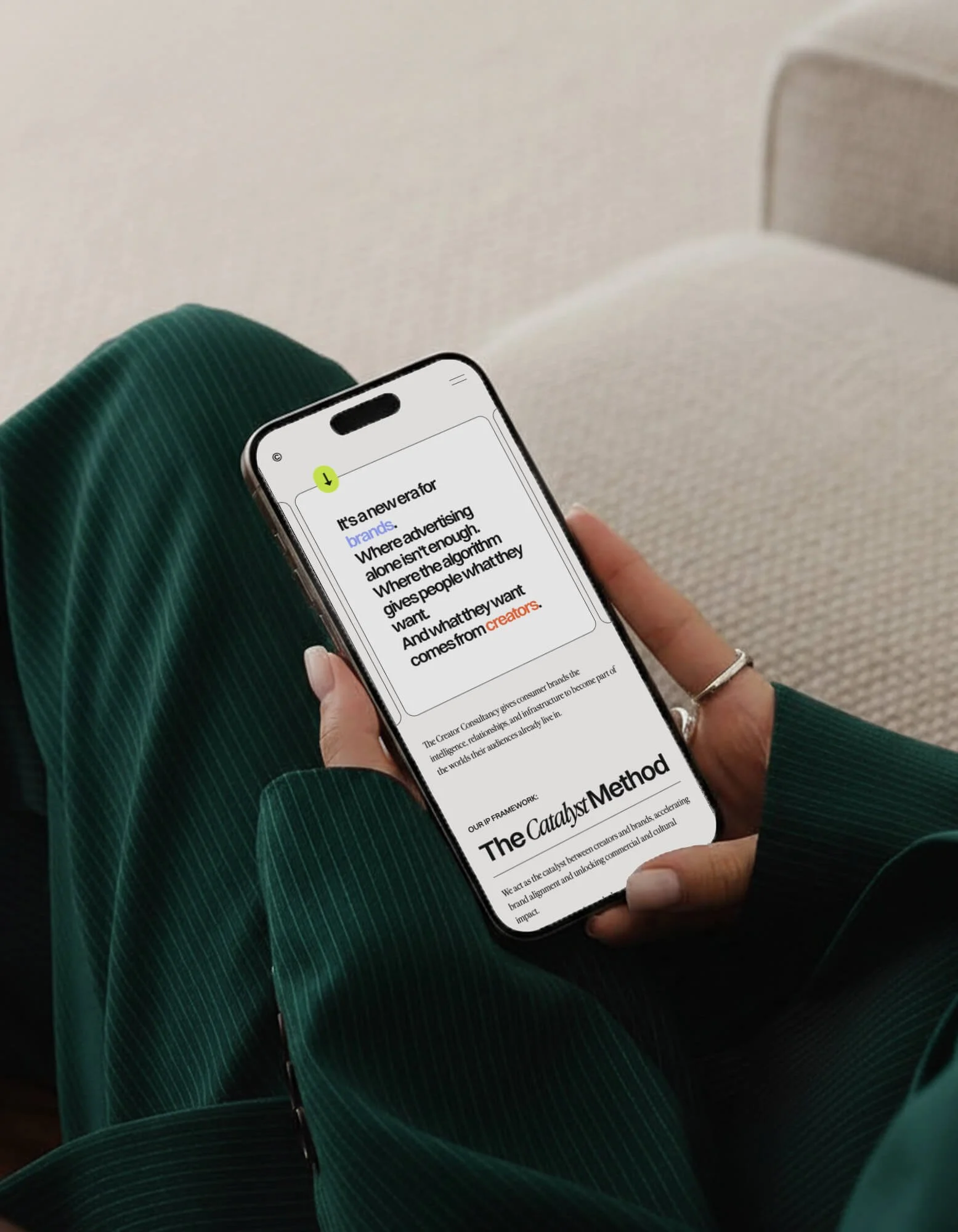 Person wearing green striped clothing holding a smartphone displaying an article titled 'The Catalyst Method' with part of the text visible.