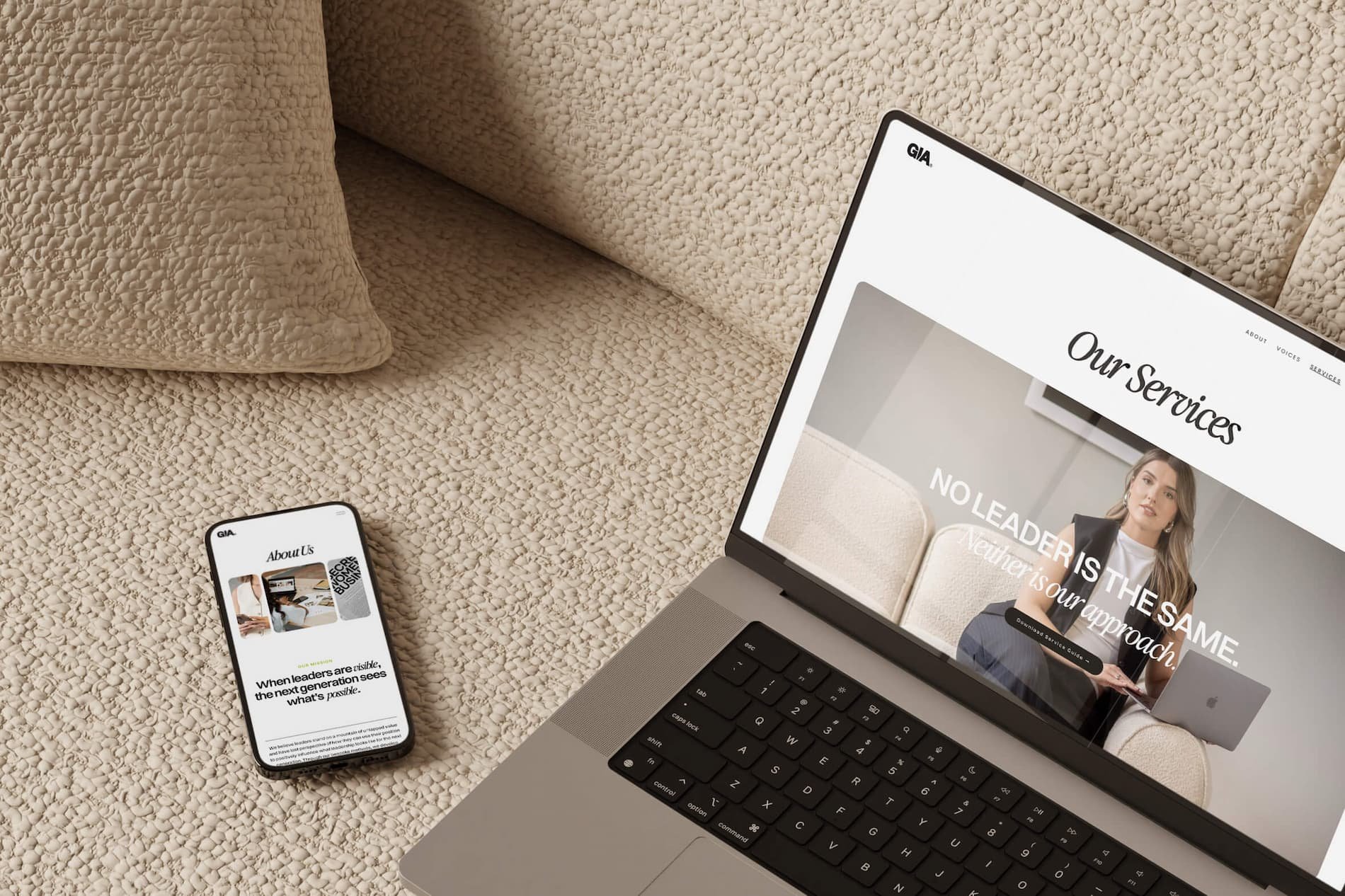 A laptop and a smartphone placed on a textured beige carpet. The laptop screen displays a website titled "Our Services" with an image of a woman. The smartphone shows a webpage titled "About Us" with images and text.