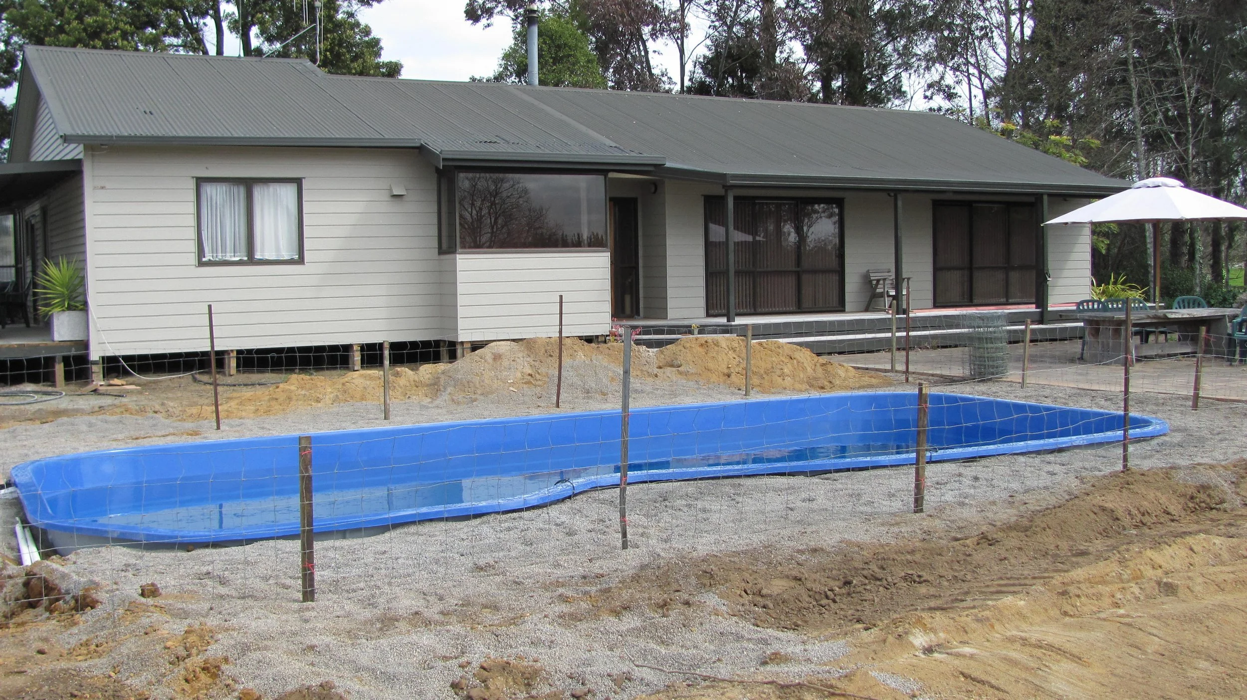 under construction backyard with a swimming pool and a house in the background