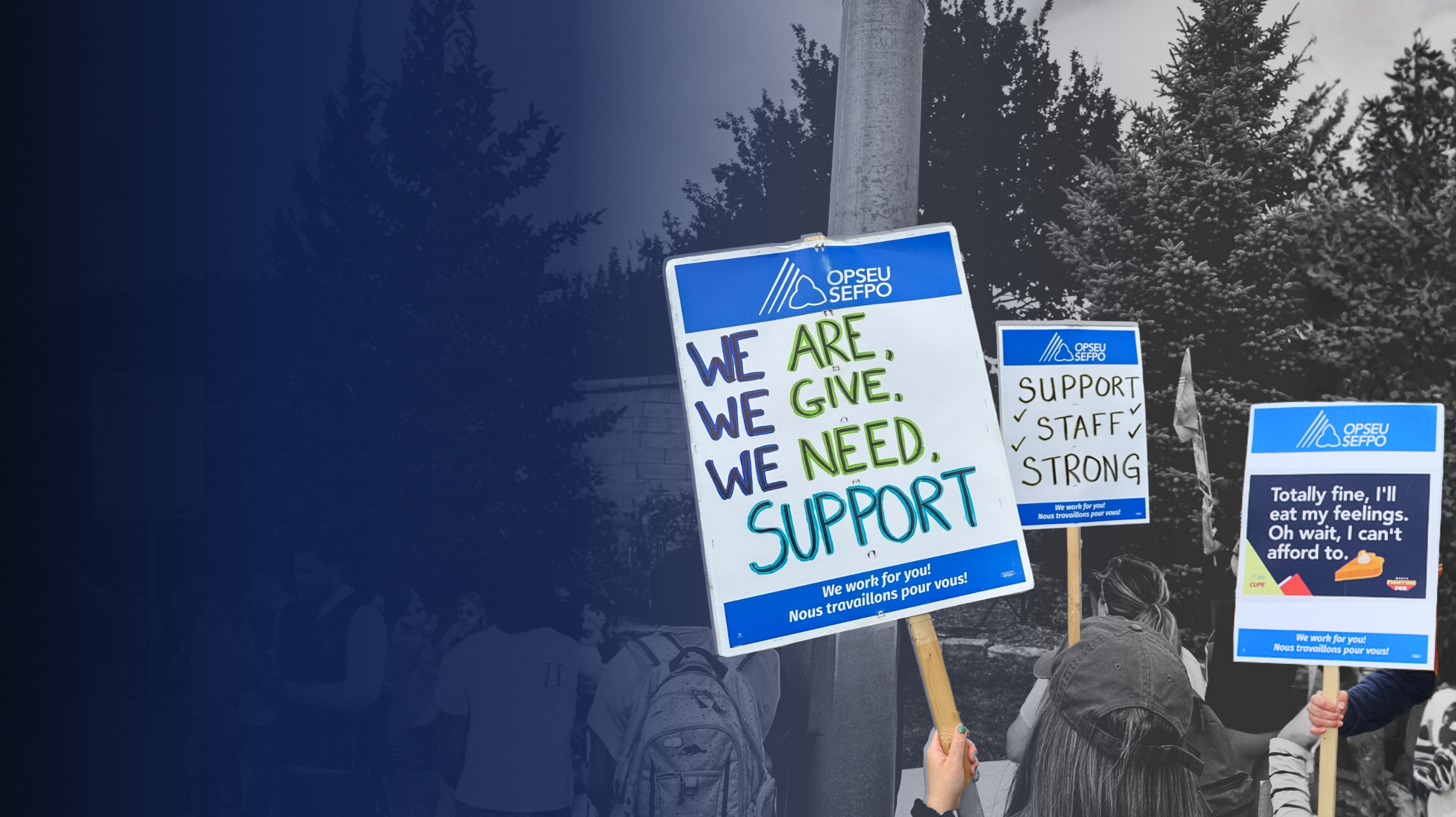 People holding signs supporting workers, with messages such as "We are, We give, We need, Support," and "Support, Staff, Strong," during a protest or rally outdoors, with trees and a cloudy sky in the background. Ram Selvarajah for OPSEU