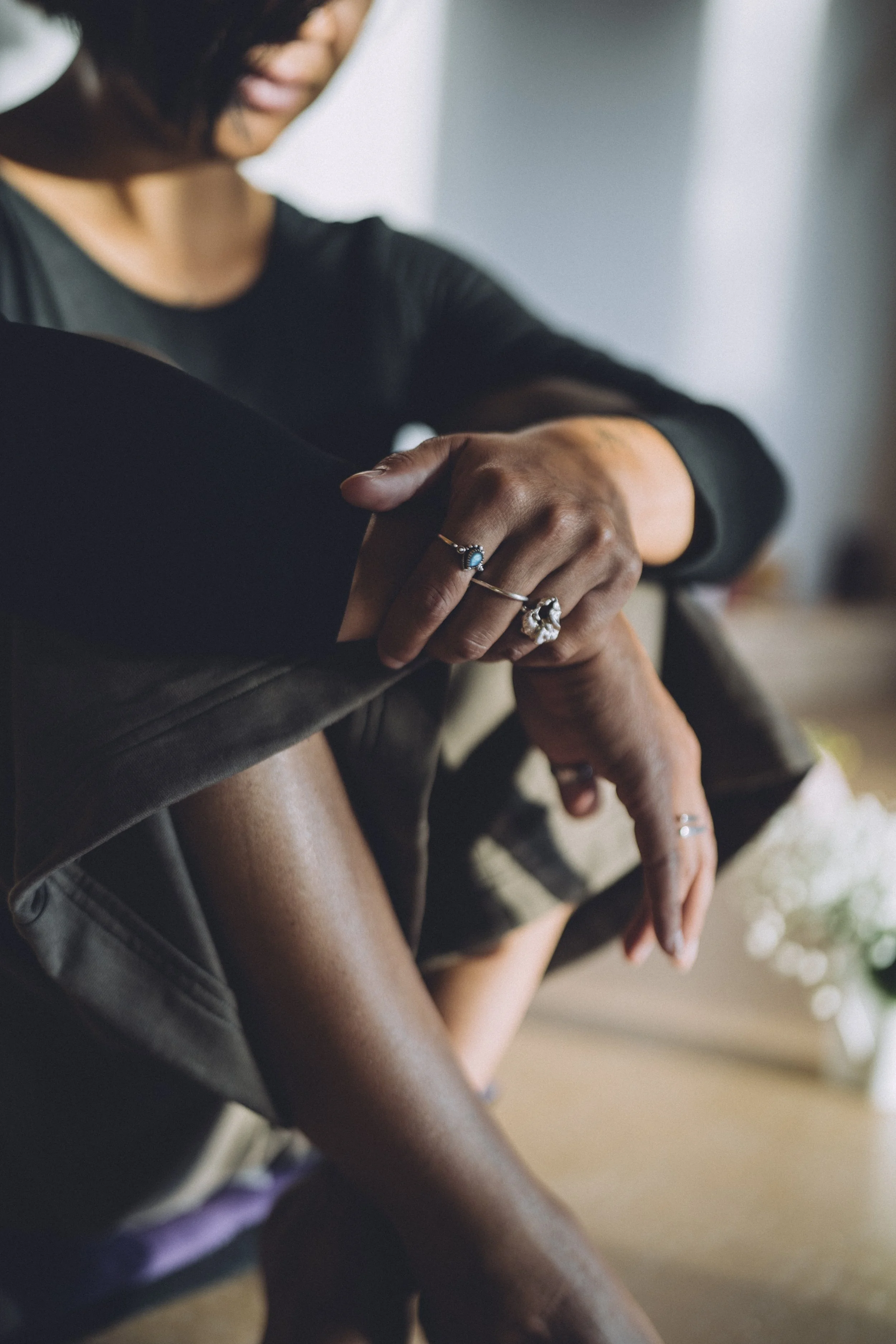Deux personnes en interaction, une personne couronnée de bijoux et portant un vêtement noir, touche le bras d'une autre personne dont la peau est foncée. La scène se déroule dans un espace intérieur avec un éclairage doux.