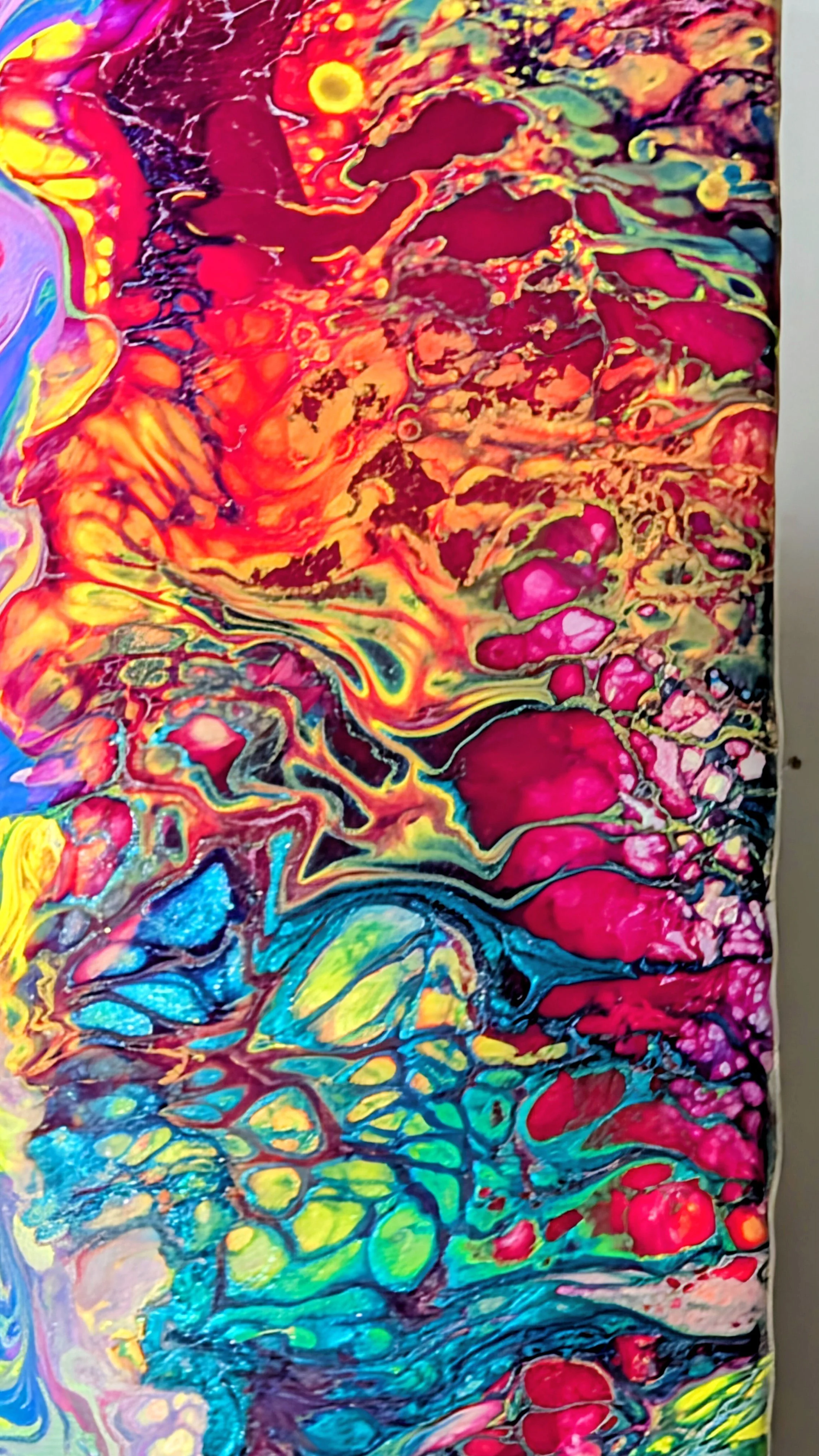 Abstract acrylic pour painting with swirling patterns and bright colors including red, pink, yellow, blue, green, and black.