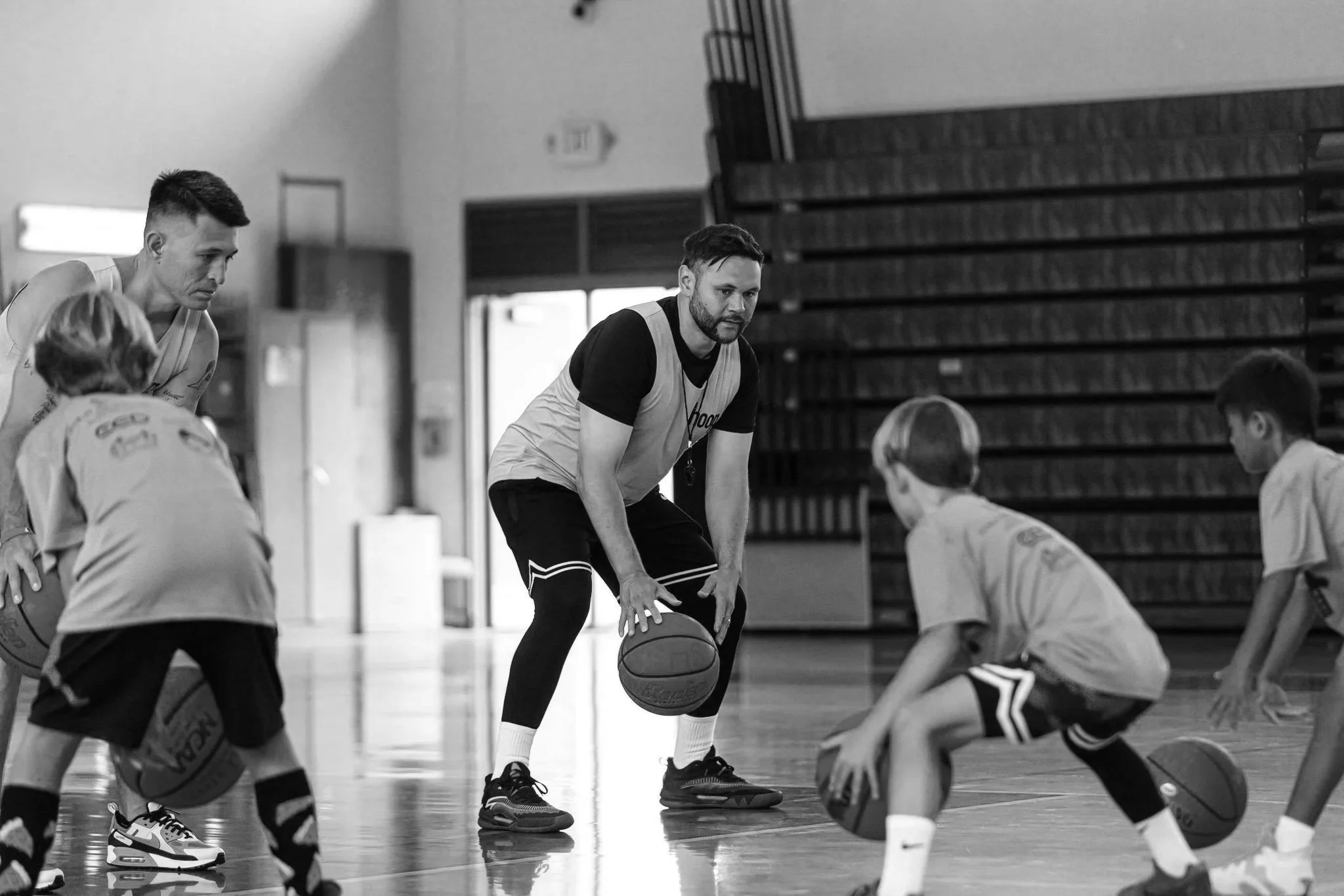 Basketball coach instructing young players during practice in a gym.