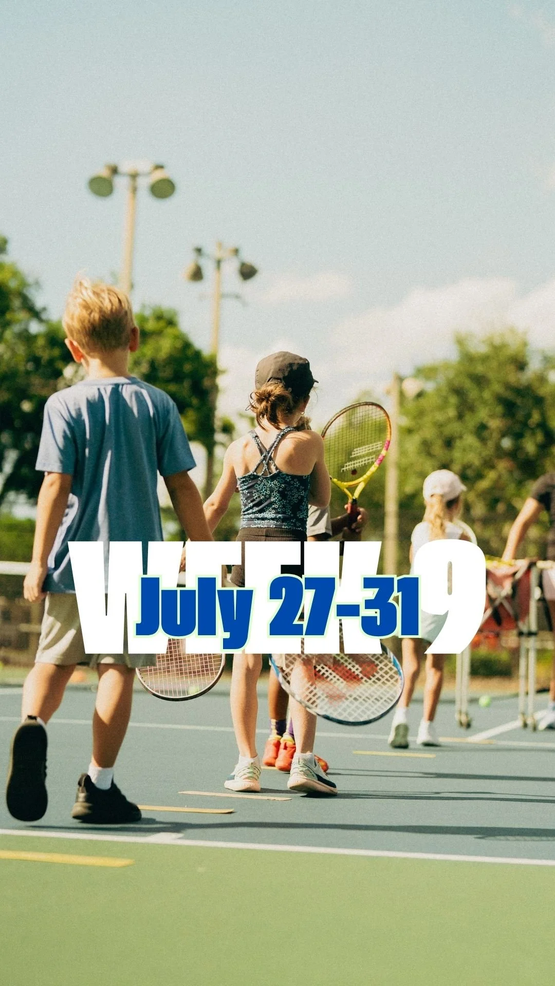 Children playing tennis on an outdoor court during summer, with trees and blue sky in the background.