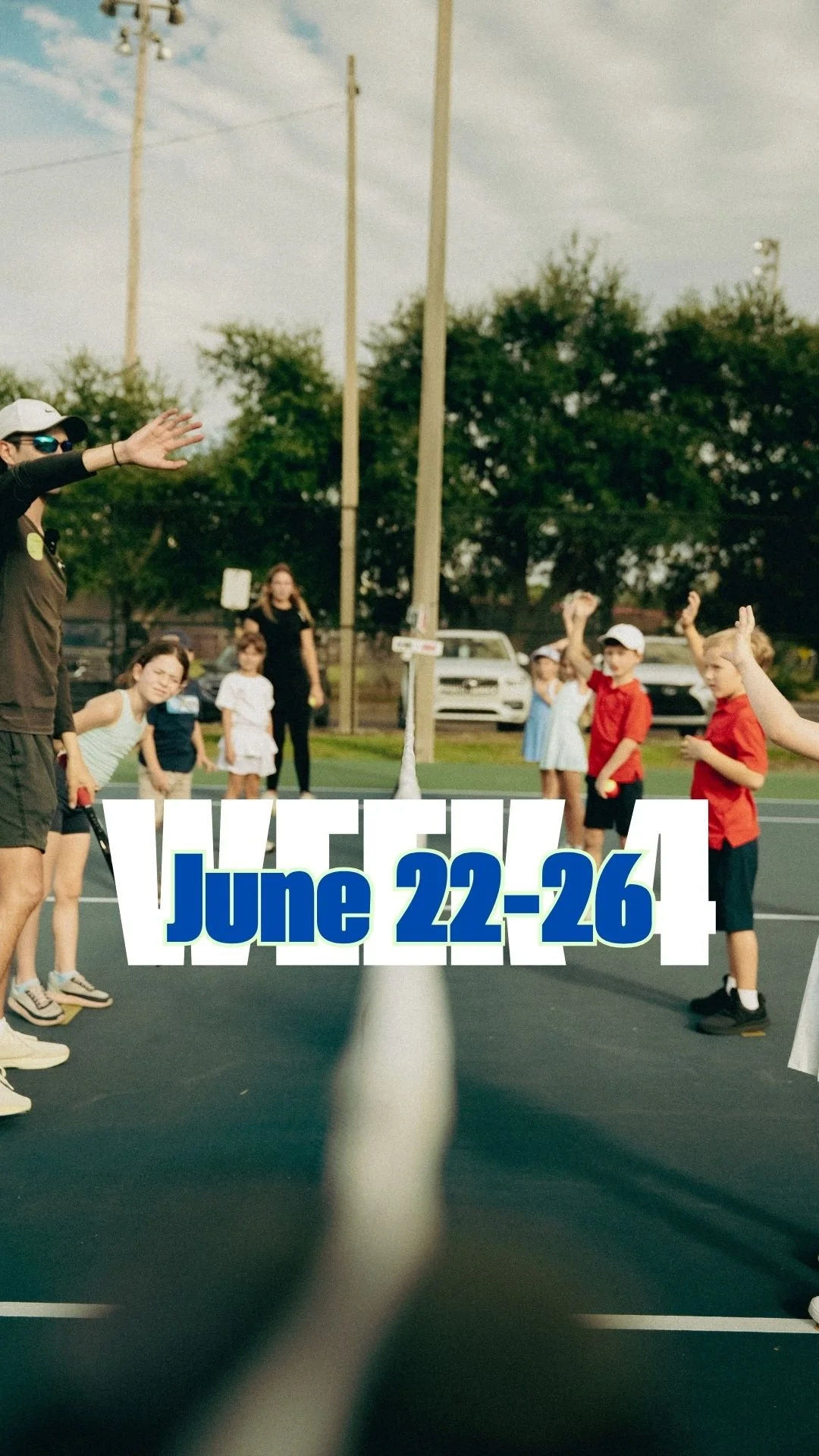 Children and adults playing tetherball outdoors with a pole in the center and a rope around it, on a sunny day.