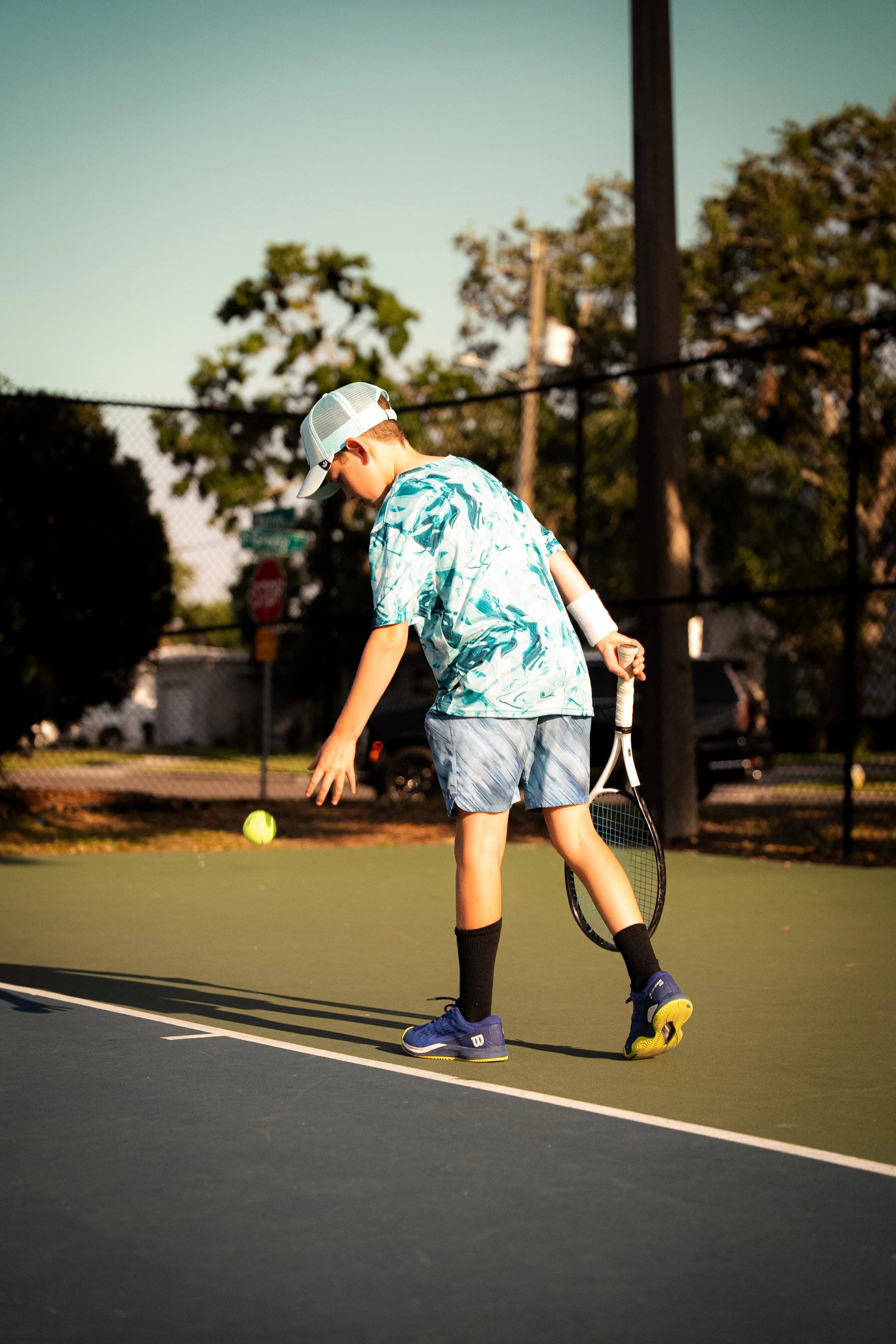 A boy on a tennis court preparing to hit a tennis ball with a racquet.