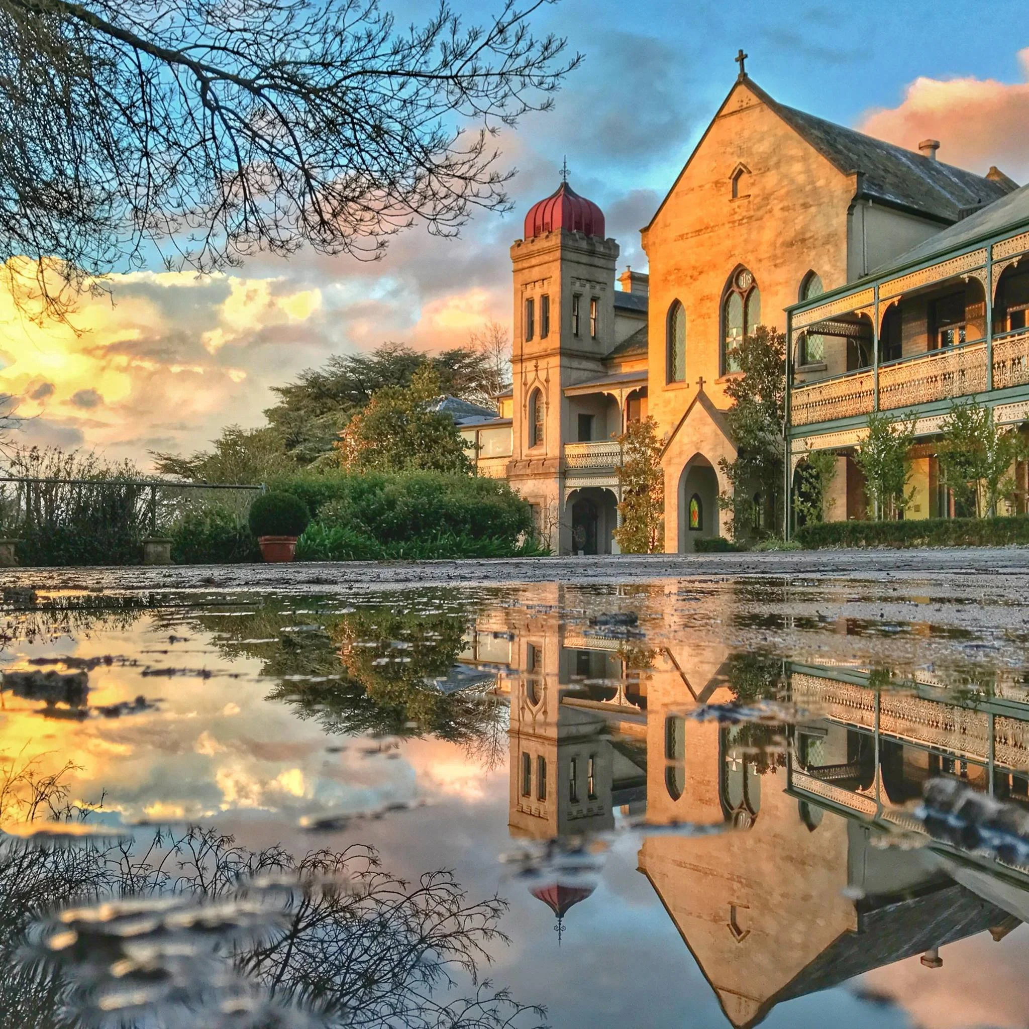 A photo of the Convent Gallery taken at sunset after rain where the building is reflected in the water