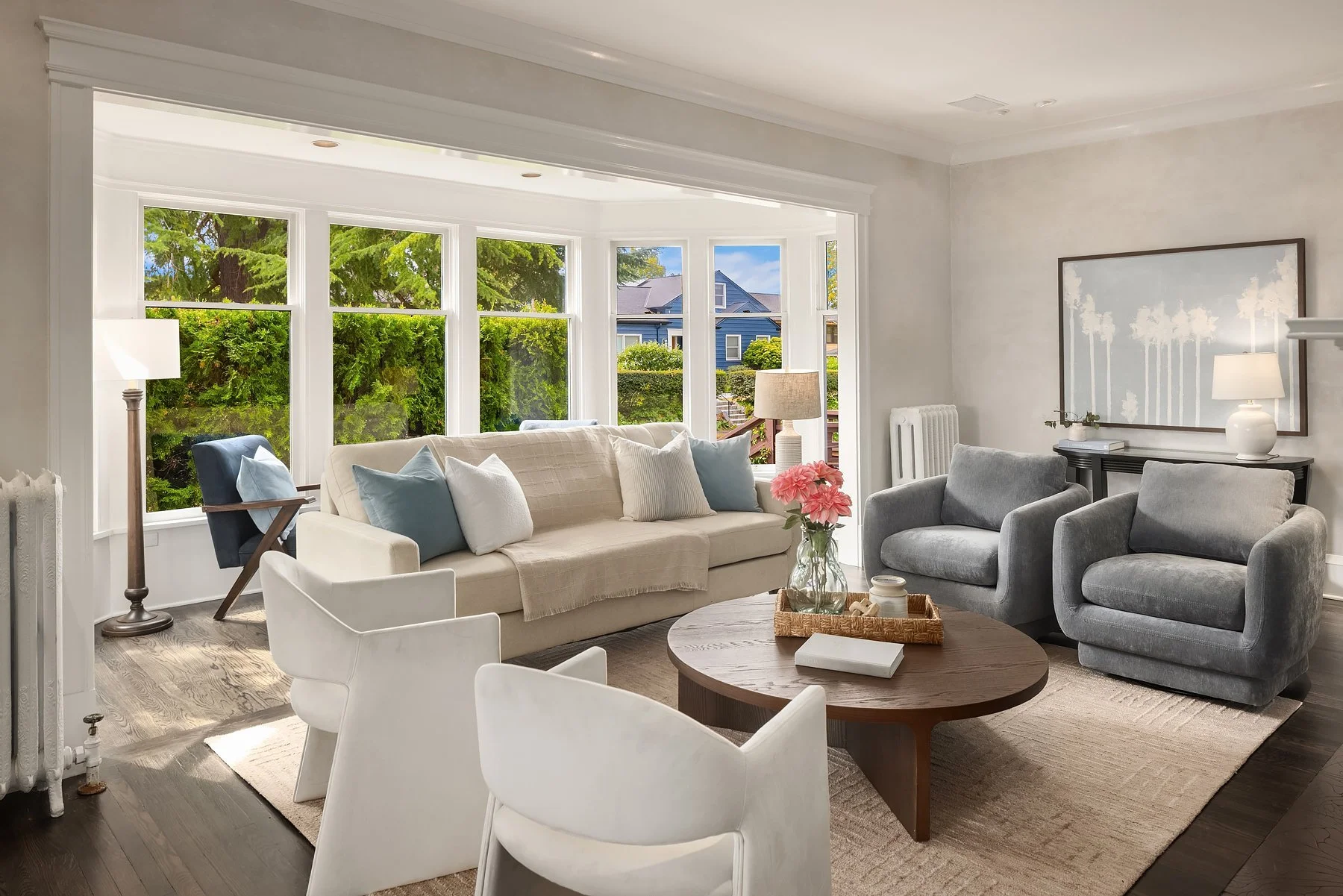 Staged living room with a wall of windows and blue-gray swivel chairs in a Seattle home
