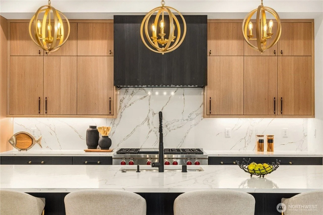 Kitchen island with marble backsplash, wood cabinetry and gold globe pendants in a Rose Hill transitional home, Redmond