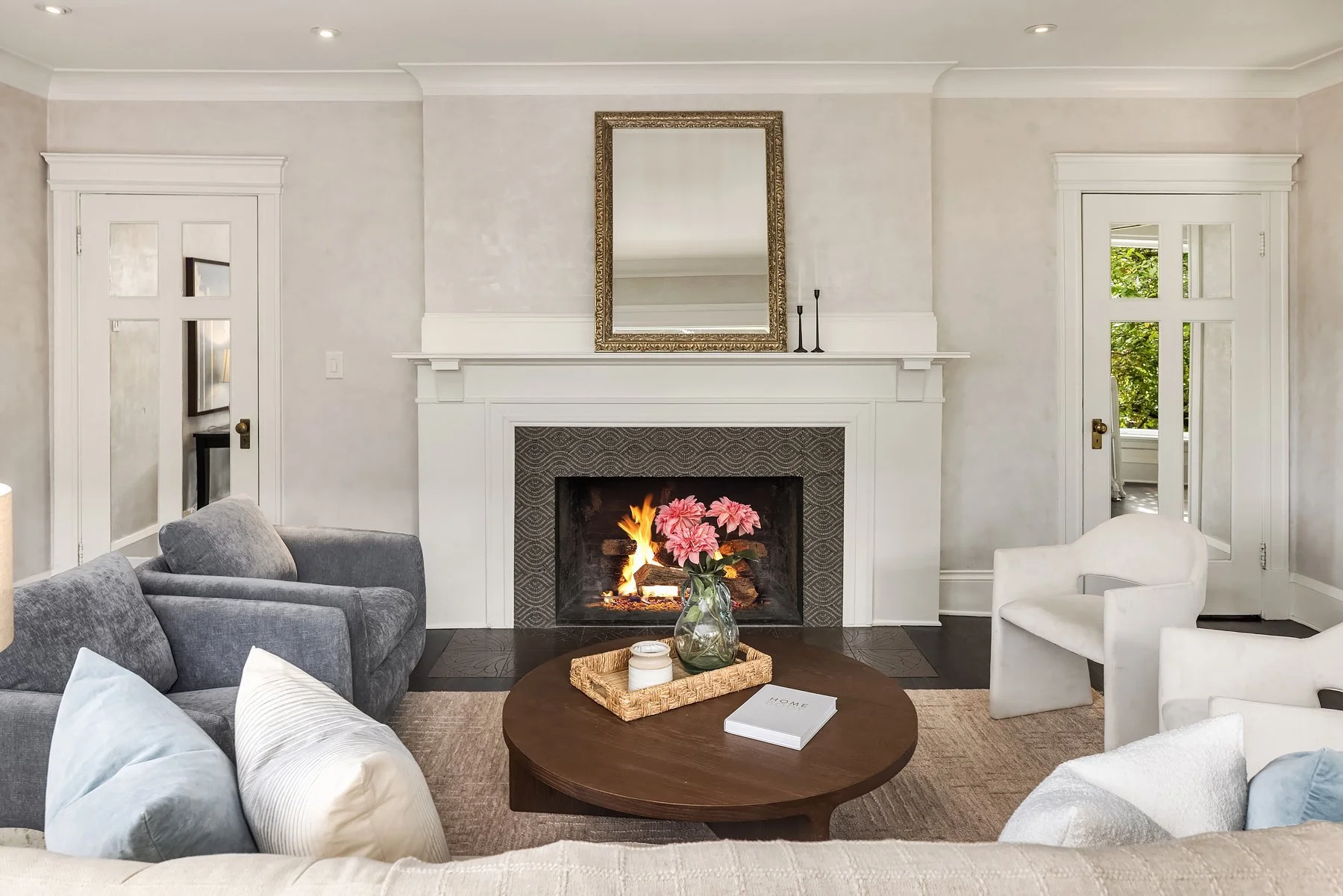 Staged living room with fireplace, mirror and sculptural white chairs in a Seattle home