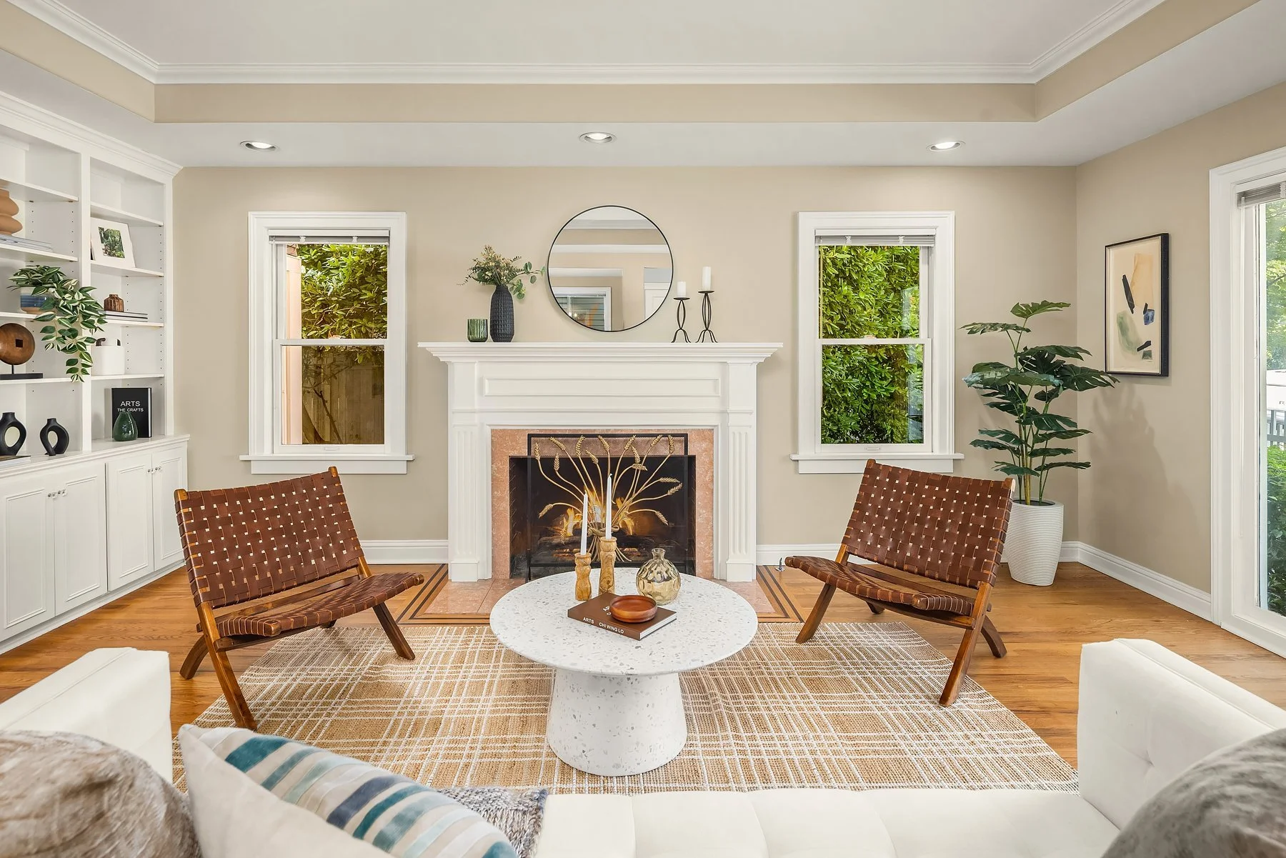 Staged living room with fireplace, round mirror and leather sling chairs in a classic Madison Park home, Seattle