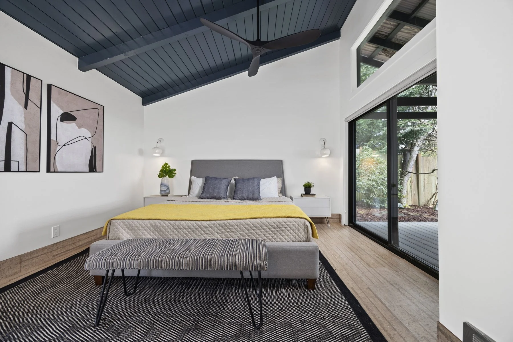 Staged primary bedroom with navy vaulted ceiling and sliding glass doors in a modern rambler, Bow WA