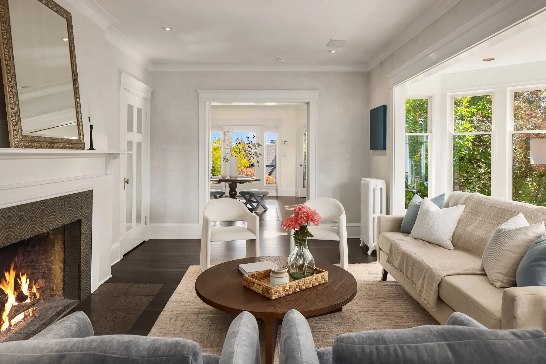 Staged living room with round wood coffee table looking toward a bright sunroom in a Seattle home
