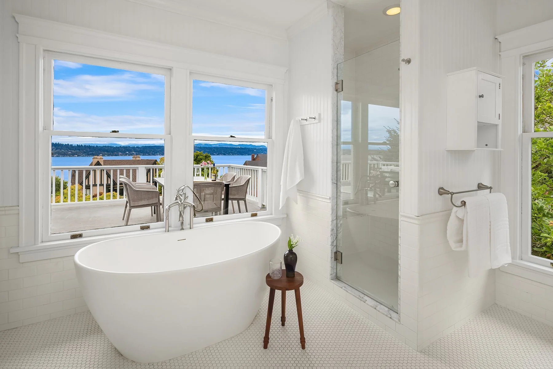 Primary bathroom with freestanding tub and water-view windows in a Seattle home