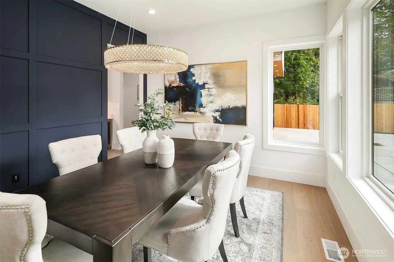 Staged dining room with navy paneled accent wall and wood table in a Rose Hill transitional home, Redmond