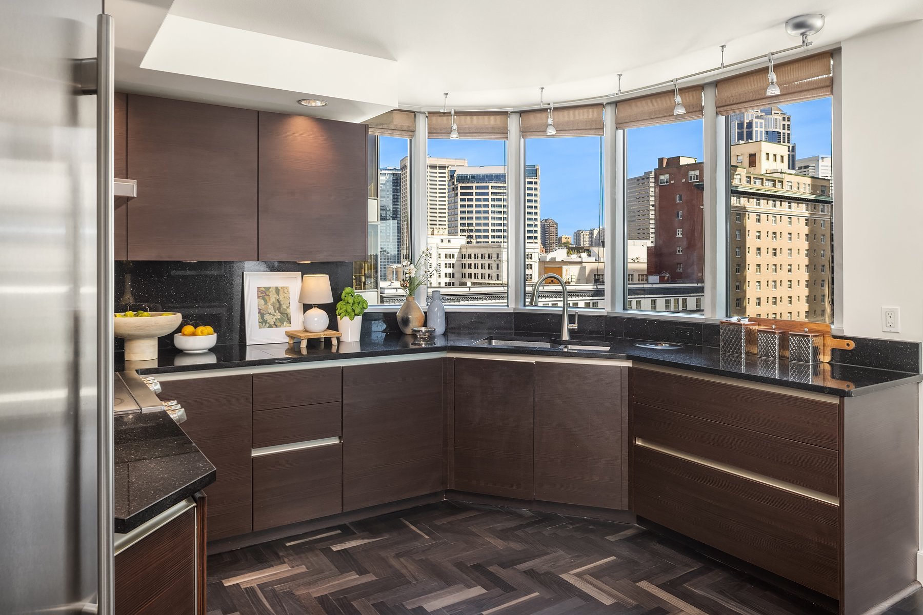 Kitchen with dark cabinetry and a curved wall of city-view windows in a downtown Seattle condo