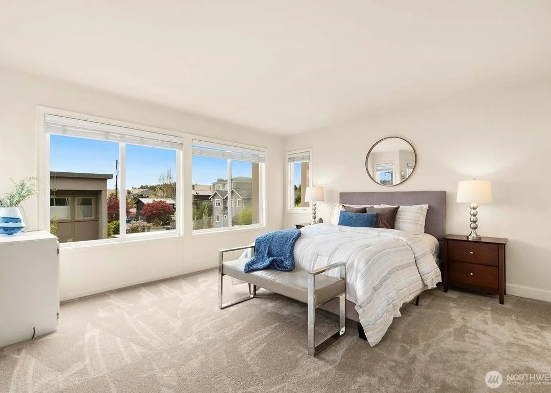 Staged bedroom with neutral bedding and a wall of windows in a Madison Park townhouse, Seattle