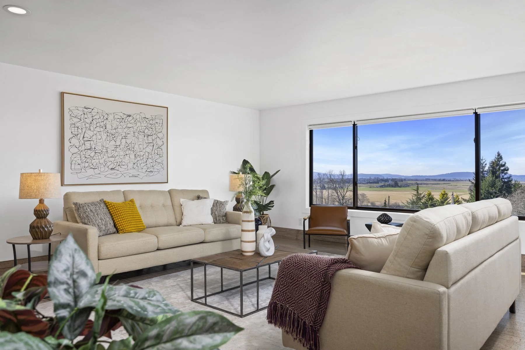 Staged family room with two sofas and a wall of view windows in a modern rambler, Bow WA