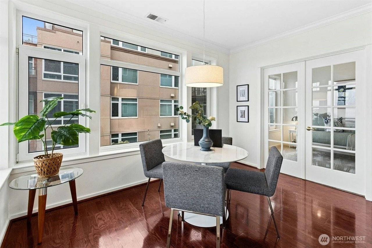 Staged dining area with round table and corner windows in a Seattle waterfront condo