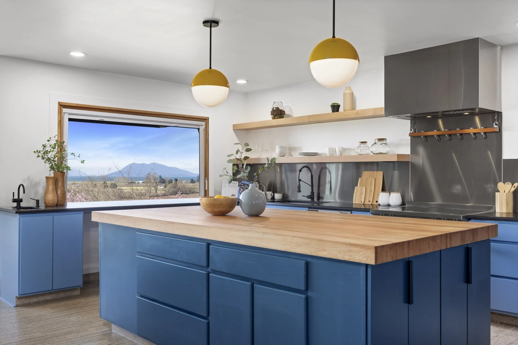 Kitchen with blue cabinetry, butcher-block island and view window in a modern rambler, Bow WA
