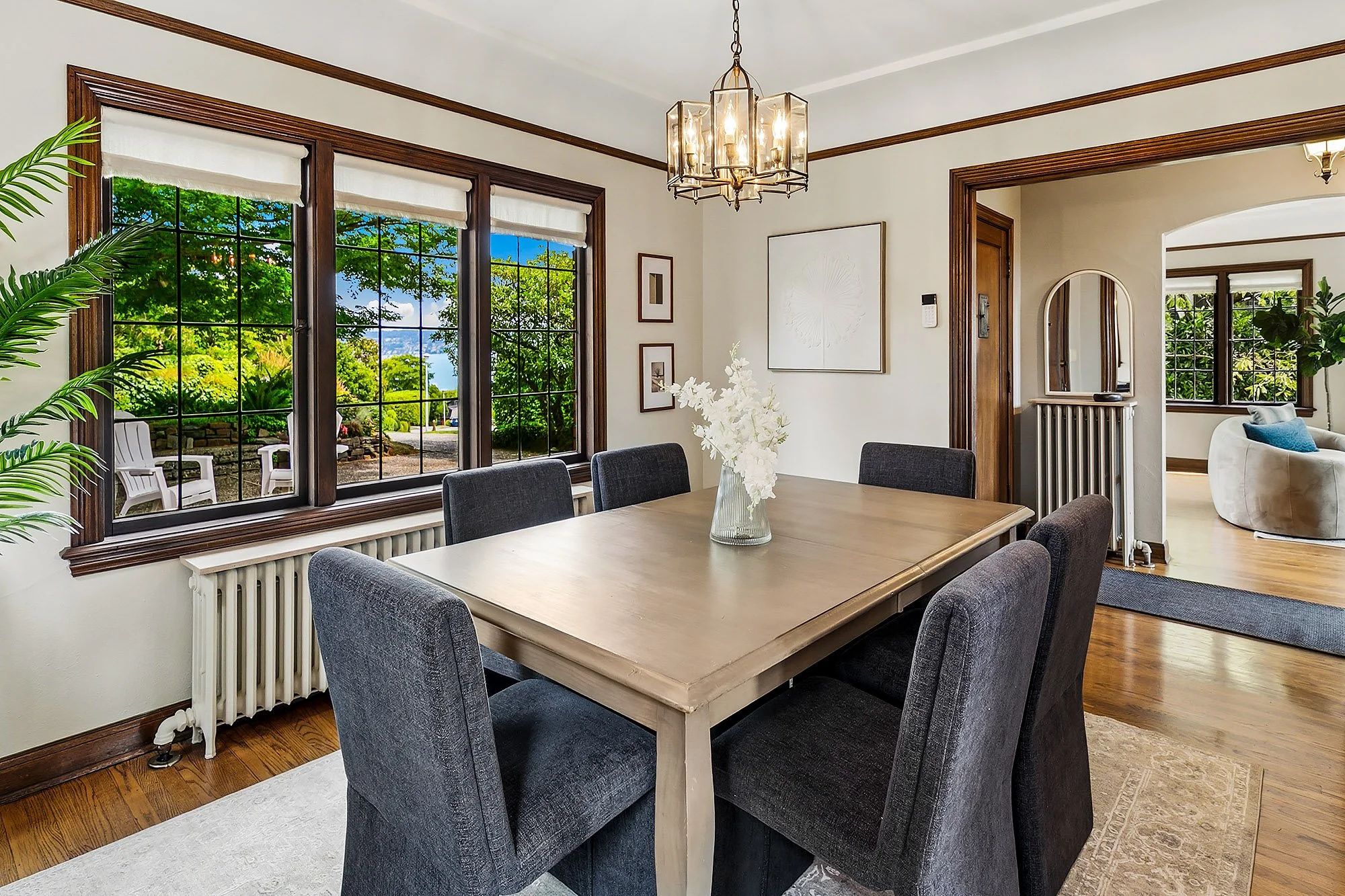 Staged dining room in a Seattle home with dark wood windows, a brass lantern chandelier and gray upholstered chairs