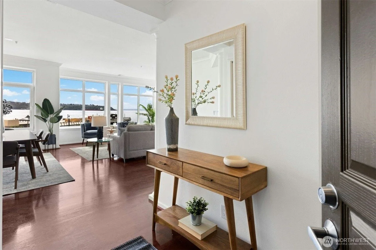 Staged entry with wood console opening to a living room with water views in a Seattle waterfront condo