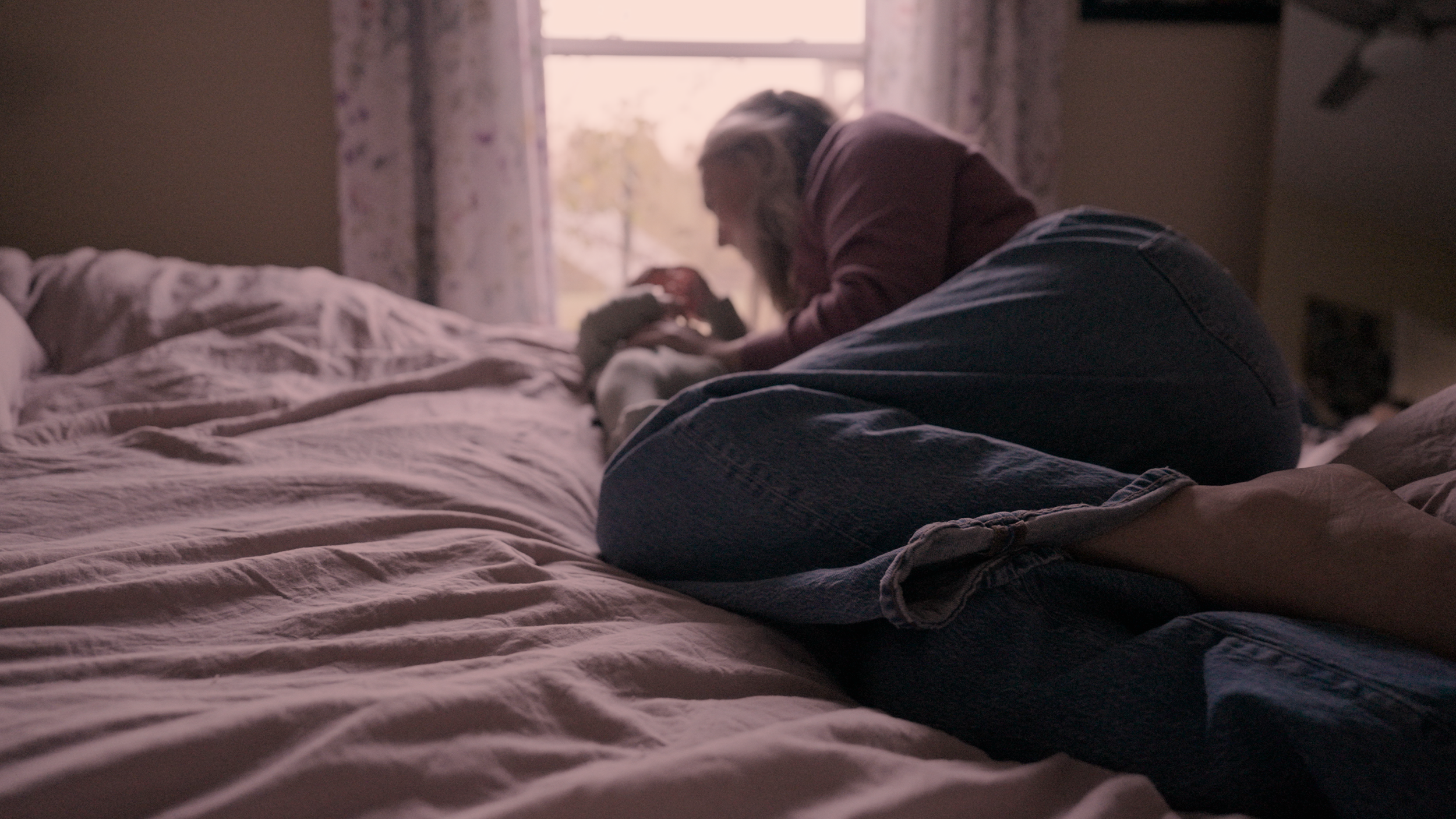 New mother lying in bed with her baby near a window — tender in-home newborn family film by Louisville videographer Tara O’Brien capturing authentic motherhood moments.