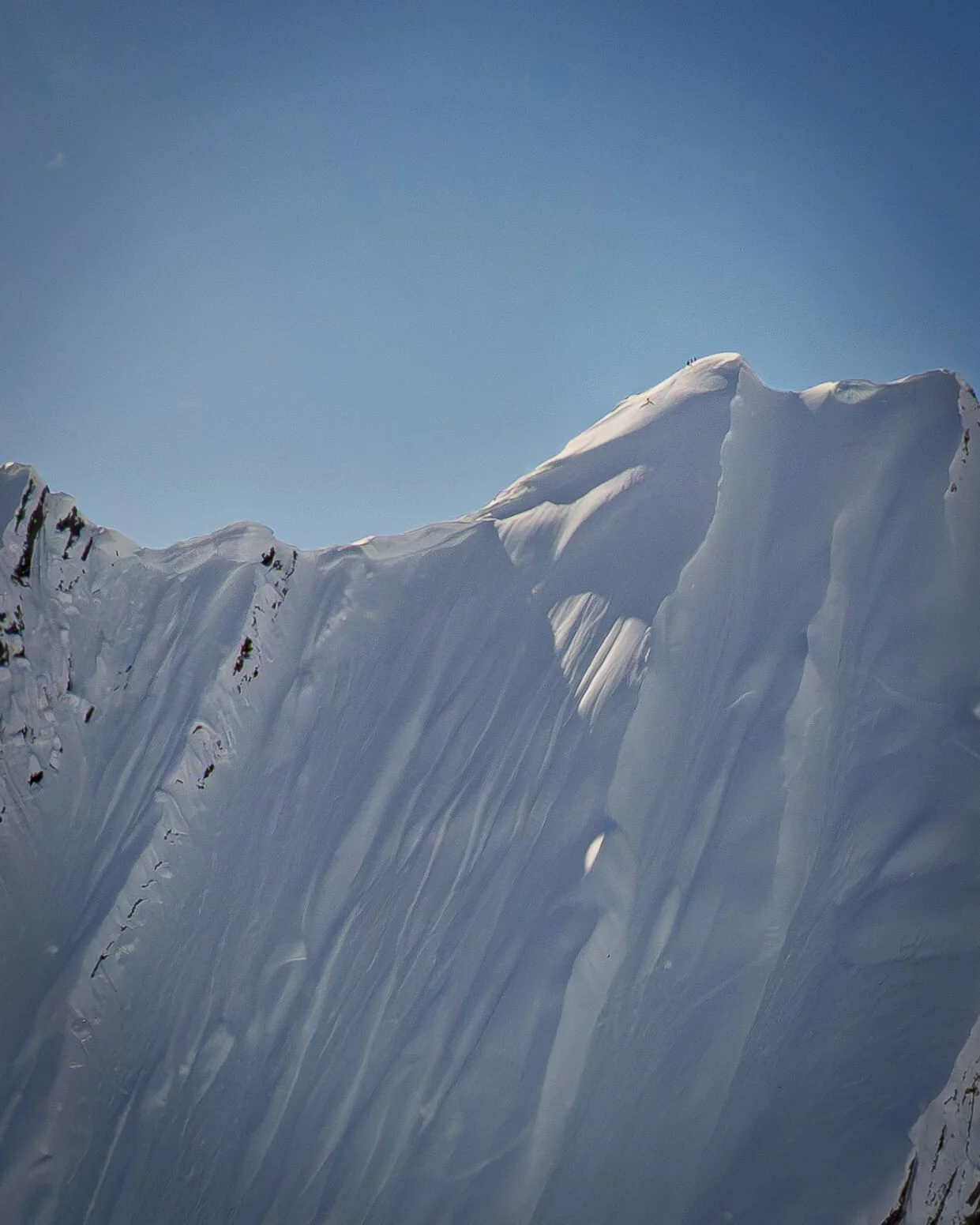 Steep, snow-covered summit framed against a blue sky.