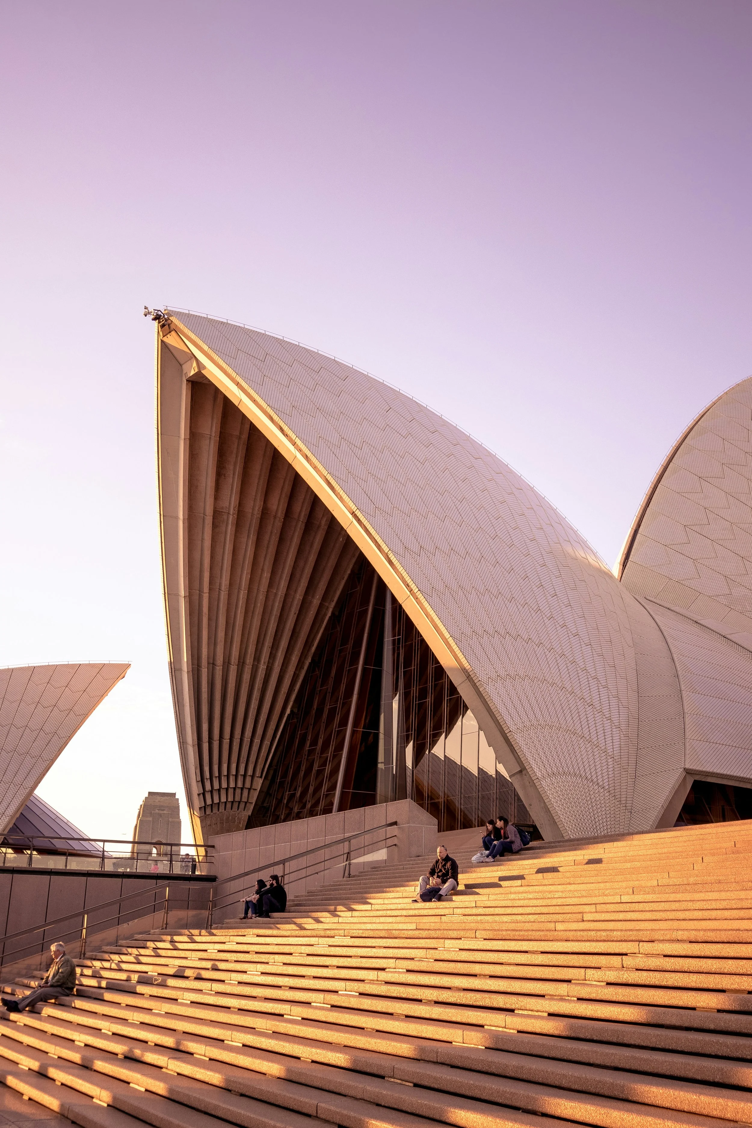 Sydney Opera House with people sitting on the stairs during sunset.
