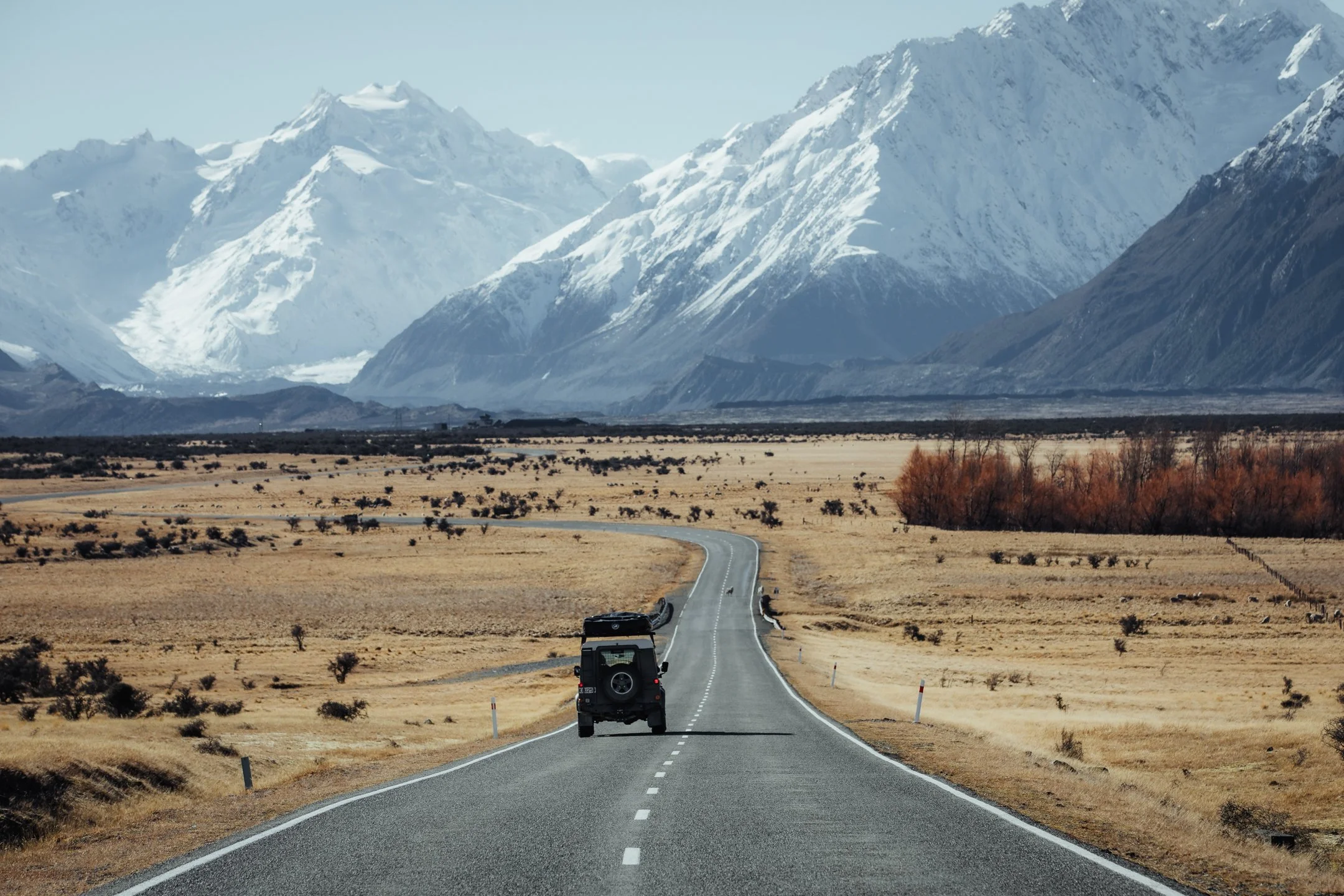 Land Rover Defender driving towards the Southern Alps on a New Zealand highway