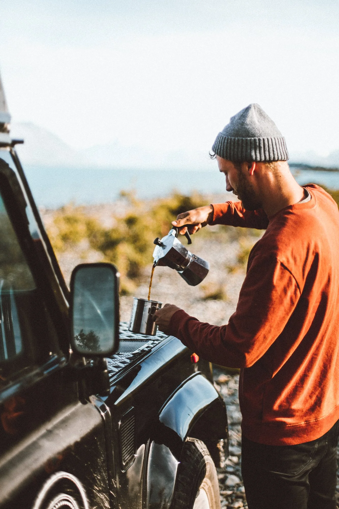 Pouring coffee beside 4WD at New Zealand lakeside camp – Trekker Adventures