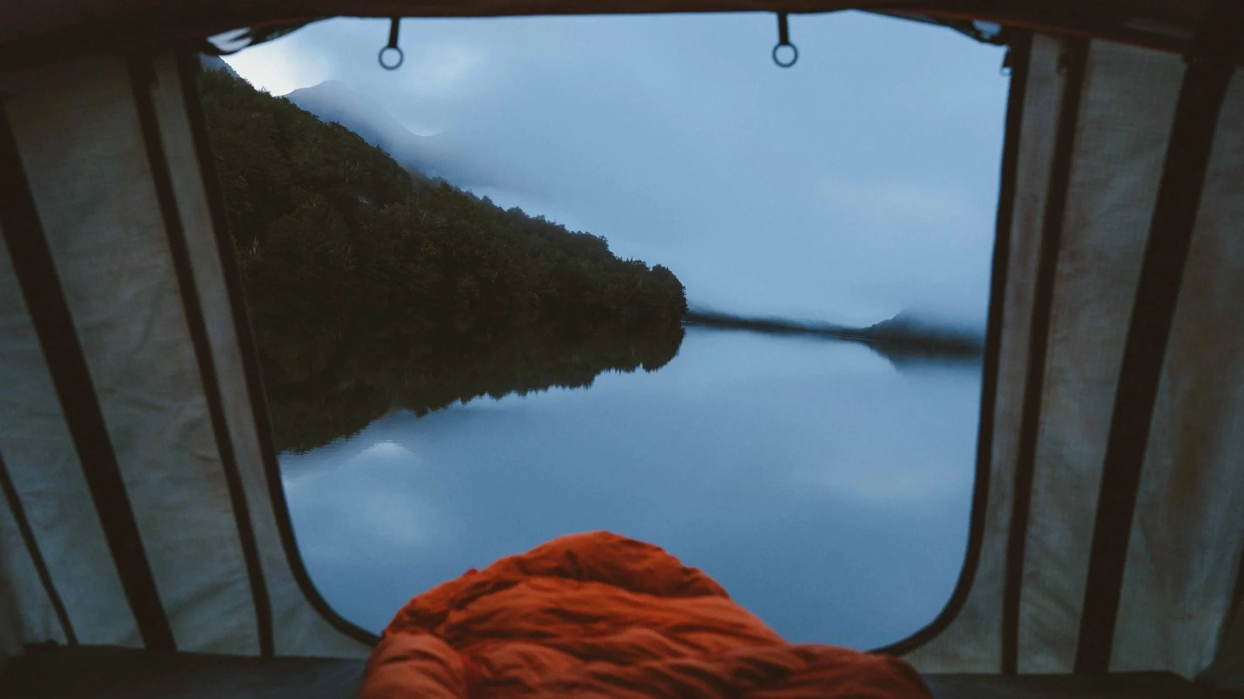 View from rooftop tent over South Island lake at dawn – Trekker Adventures