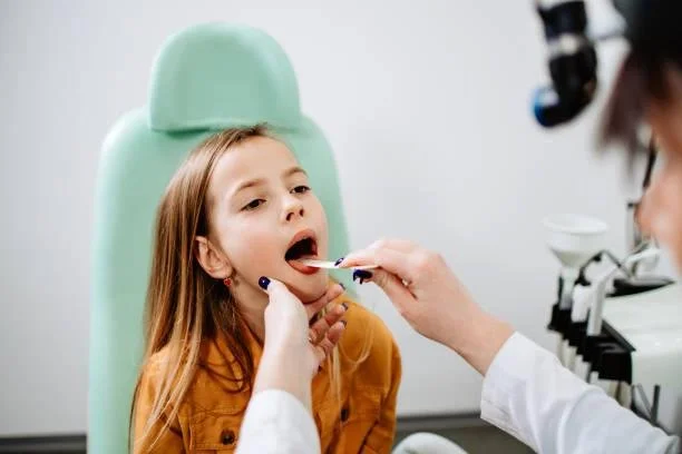 Pediatric dentist examining a child’s mouth for lip and tongue tie — gentle laser release treatment to improve speech, feeding, and oral health at Starlight Dental.