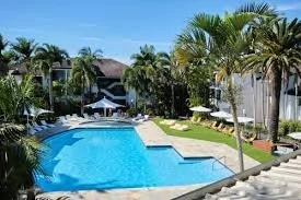 Swimming pool in a tropical setting with palm trees and lounge chairs.