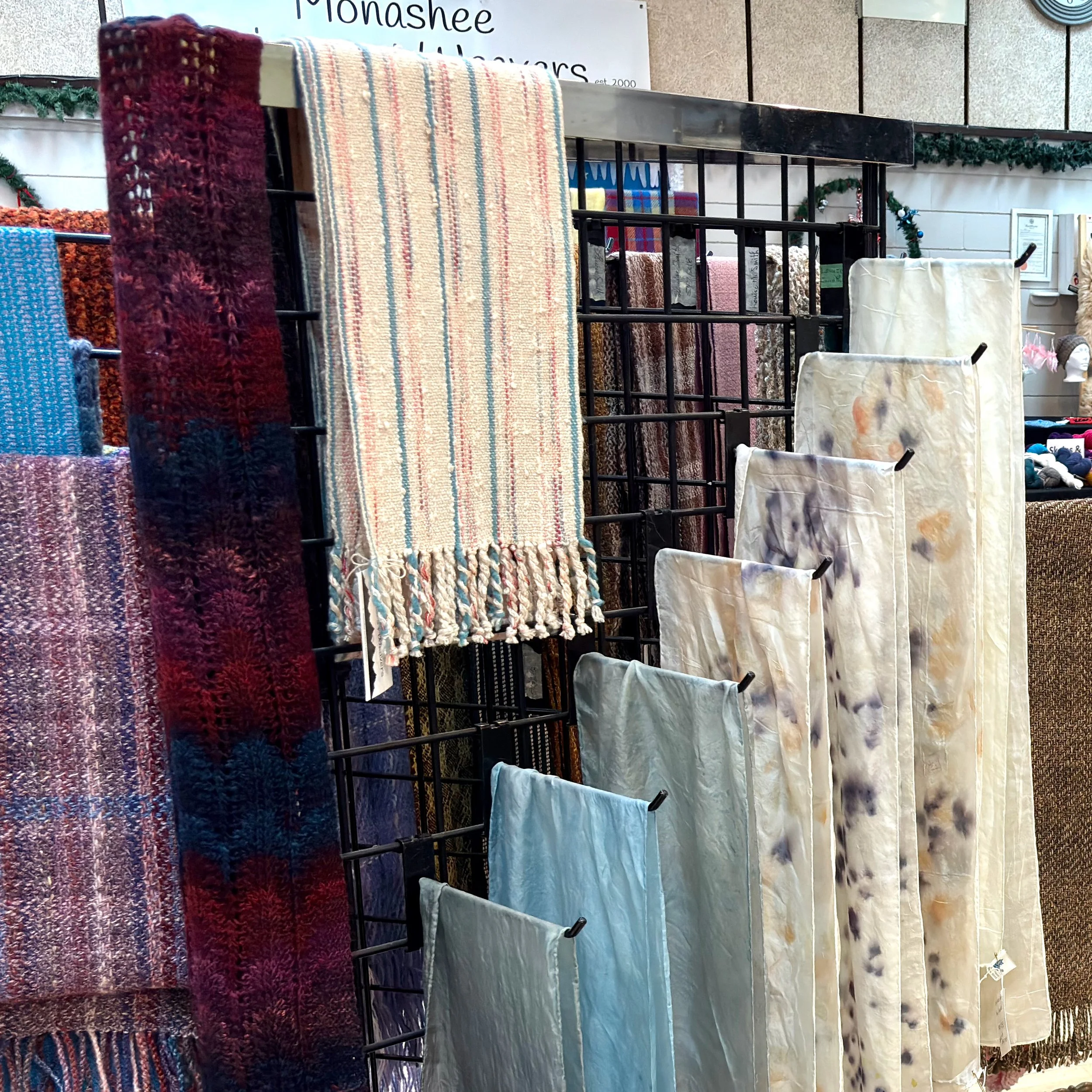 Display of various rugs and fabric swatches on a grid stand in a store, including striped, textured, and patterned designs.