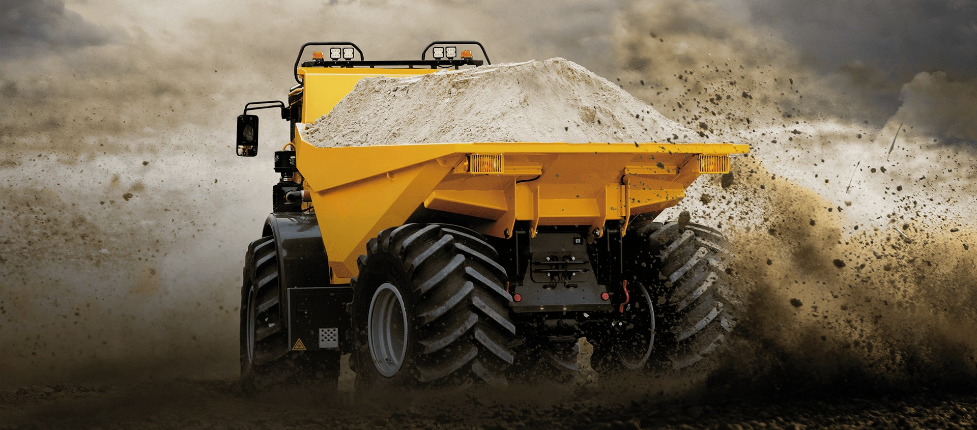 A yellow construction dump truck moving dirt on a construction site, with dust and clouds in the background.