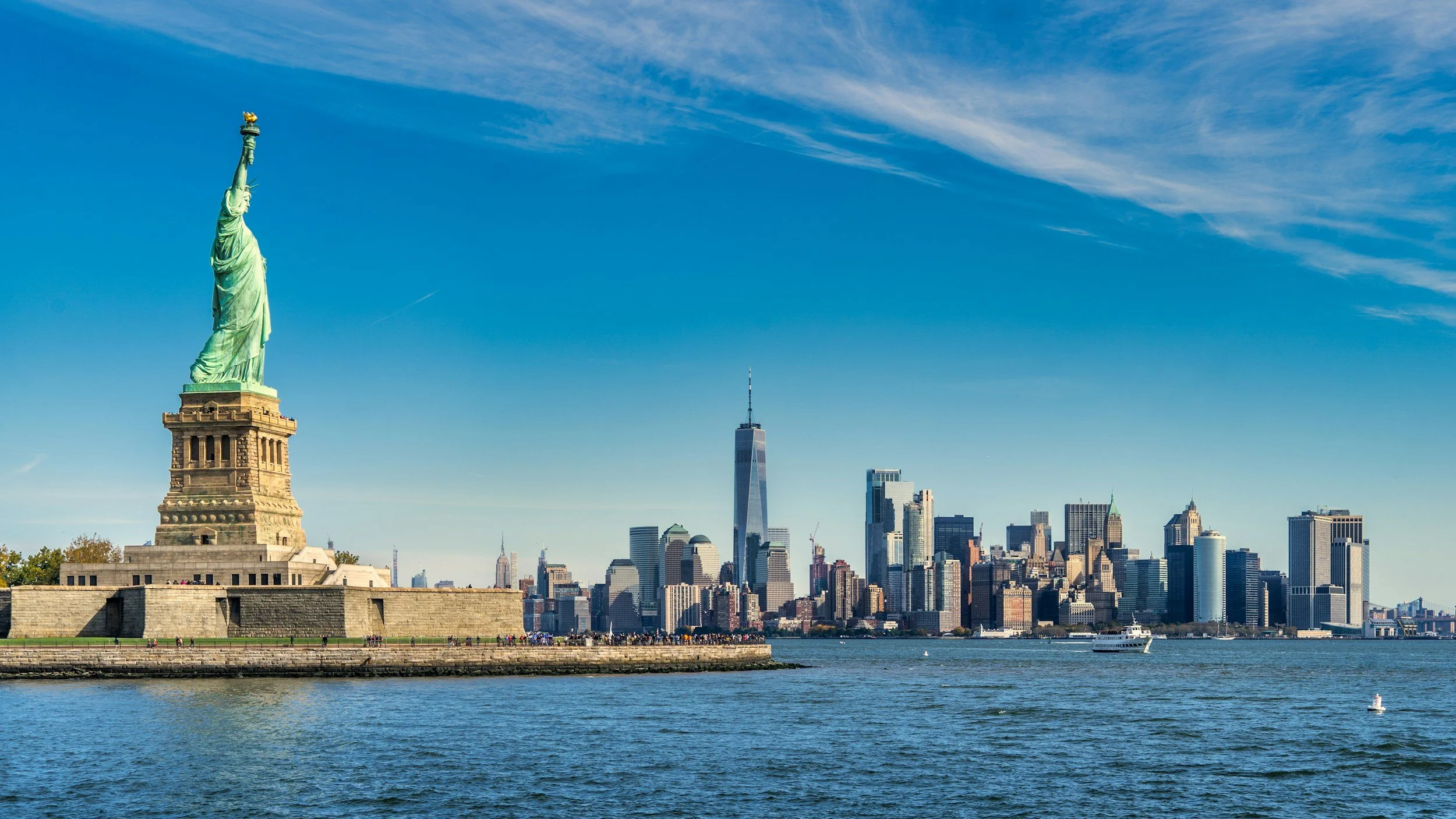 Vista del skyline de Manhattan con la Estatua de la Libertad en primer plano y el río Hudson en primer plano.