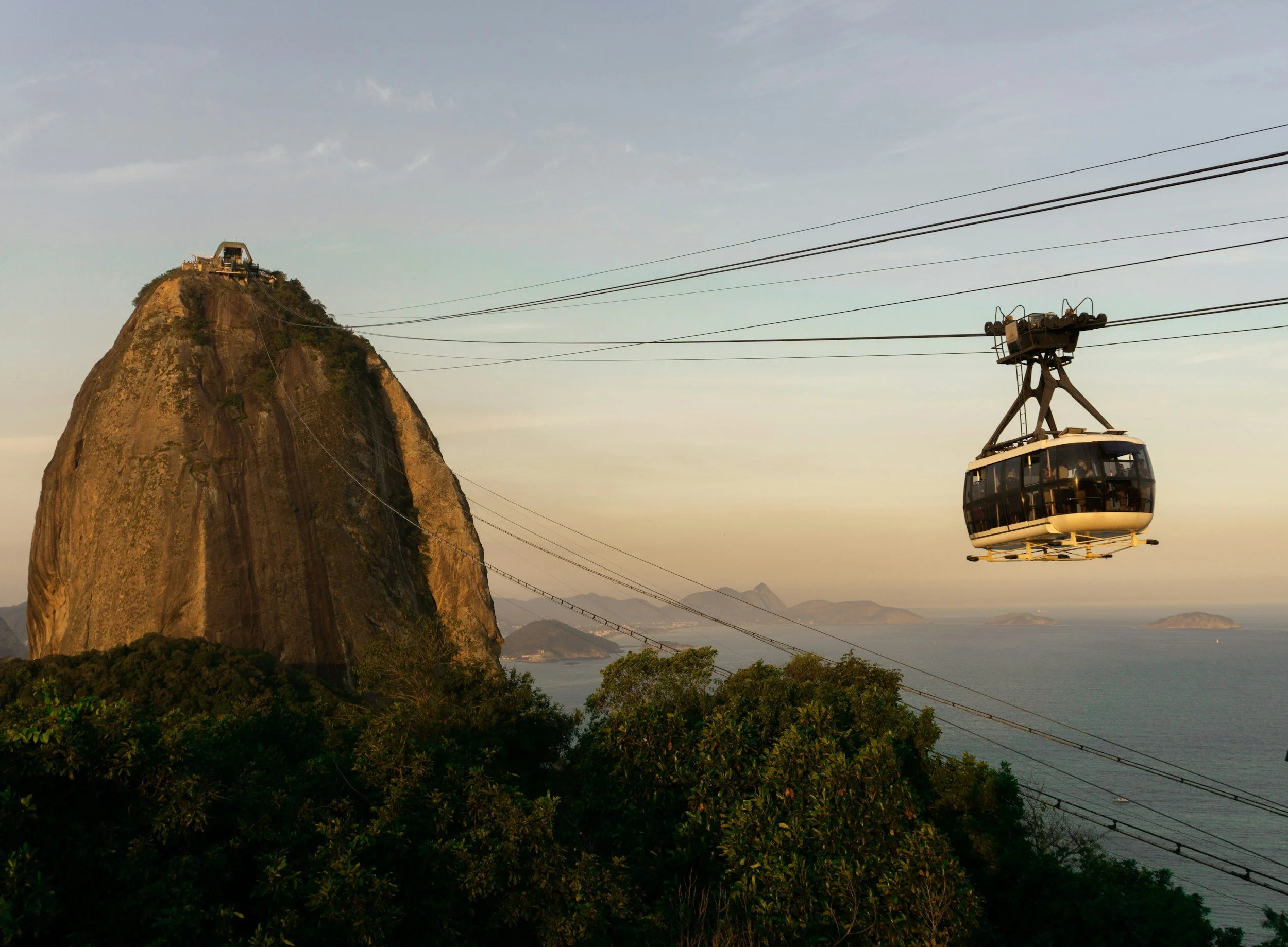 Teleférico en Río de Janeiro con el Pão de Açúcar en el fondo durante el atardecer.