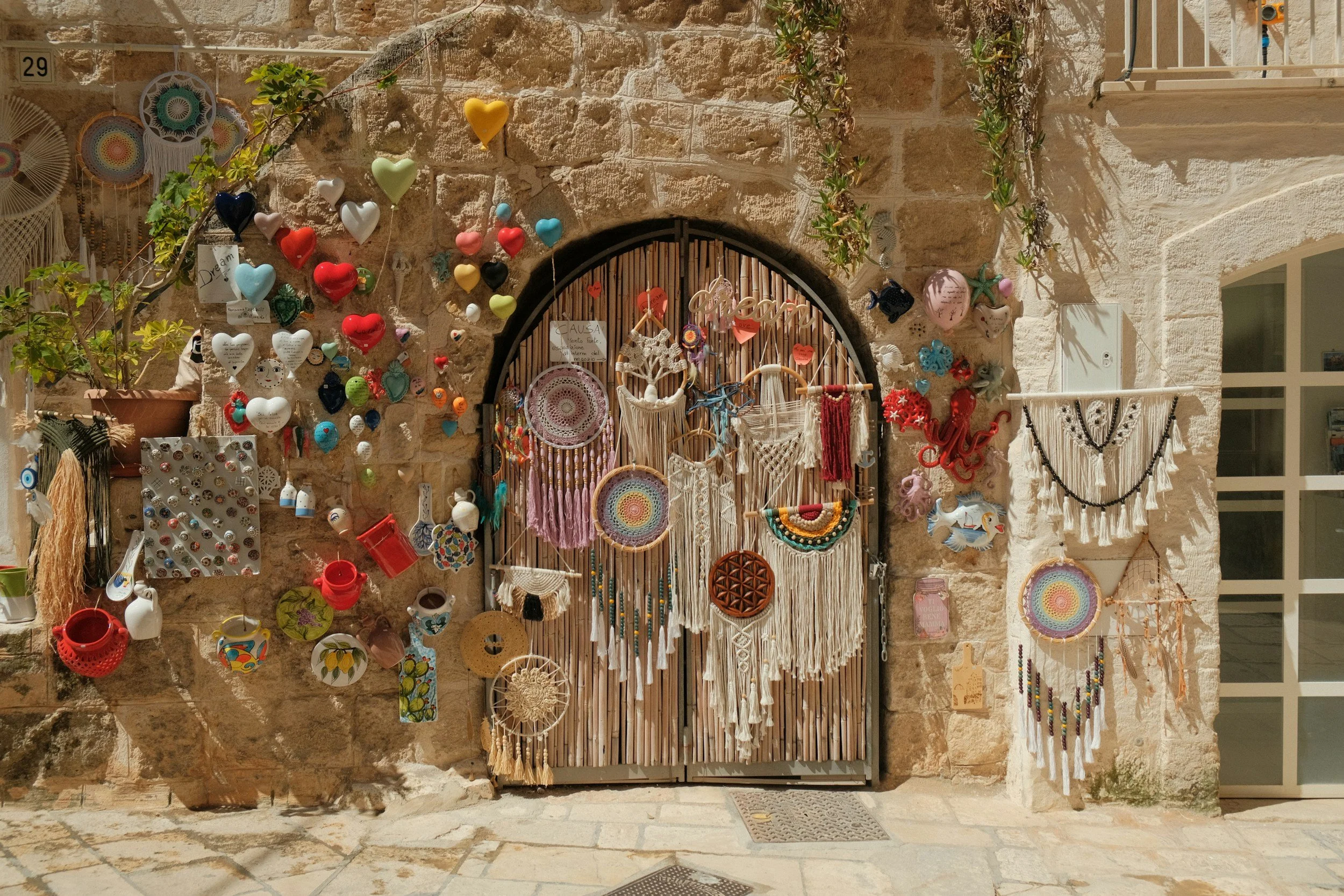 Entrada decorada con atrapas sueños, corazones de colores, y moonas en una pared de piedra.