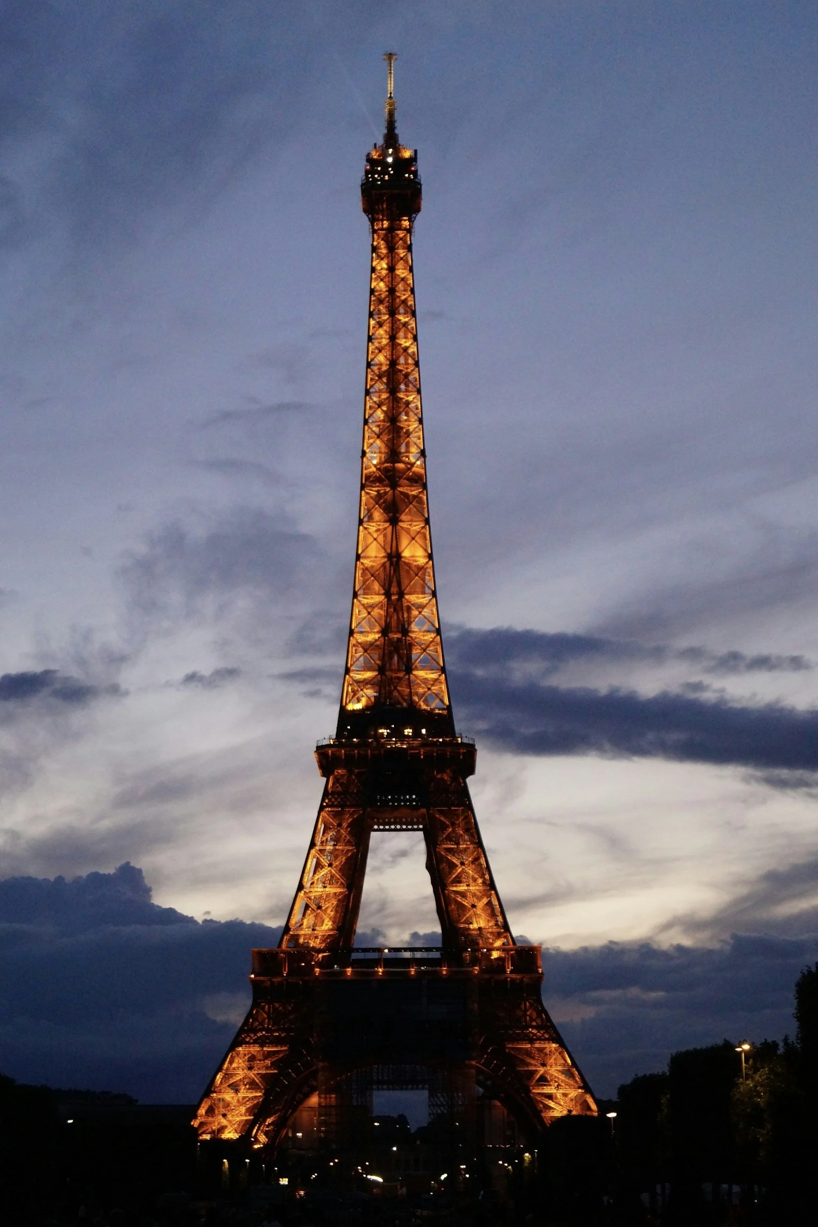 La Torre Eiffel iluminada por la noche contra un cielo oscuro con nubes.