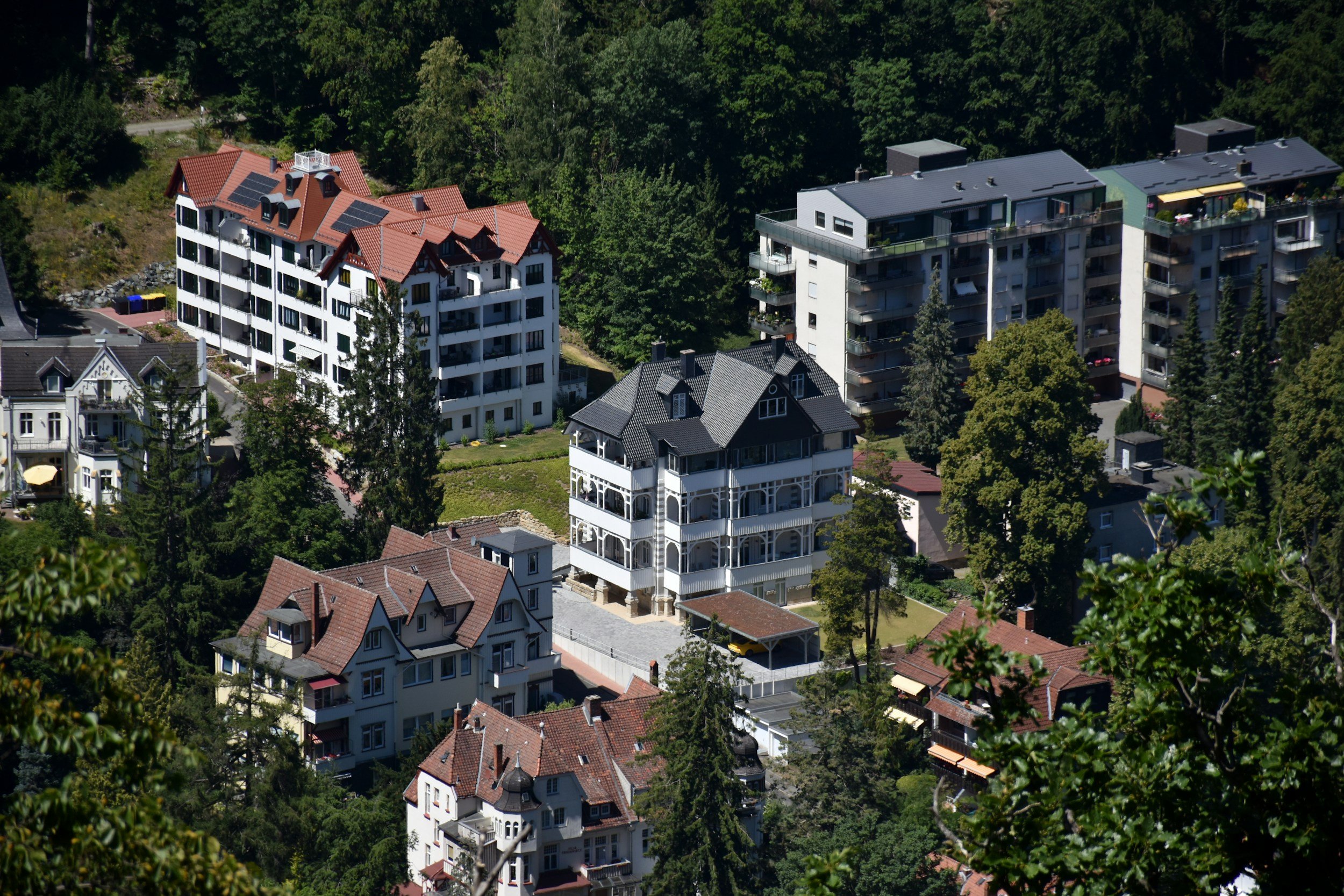 Vista aérea de varias casas y edificios residenciales rodeados de árboles verdes en una colina.