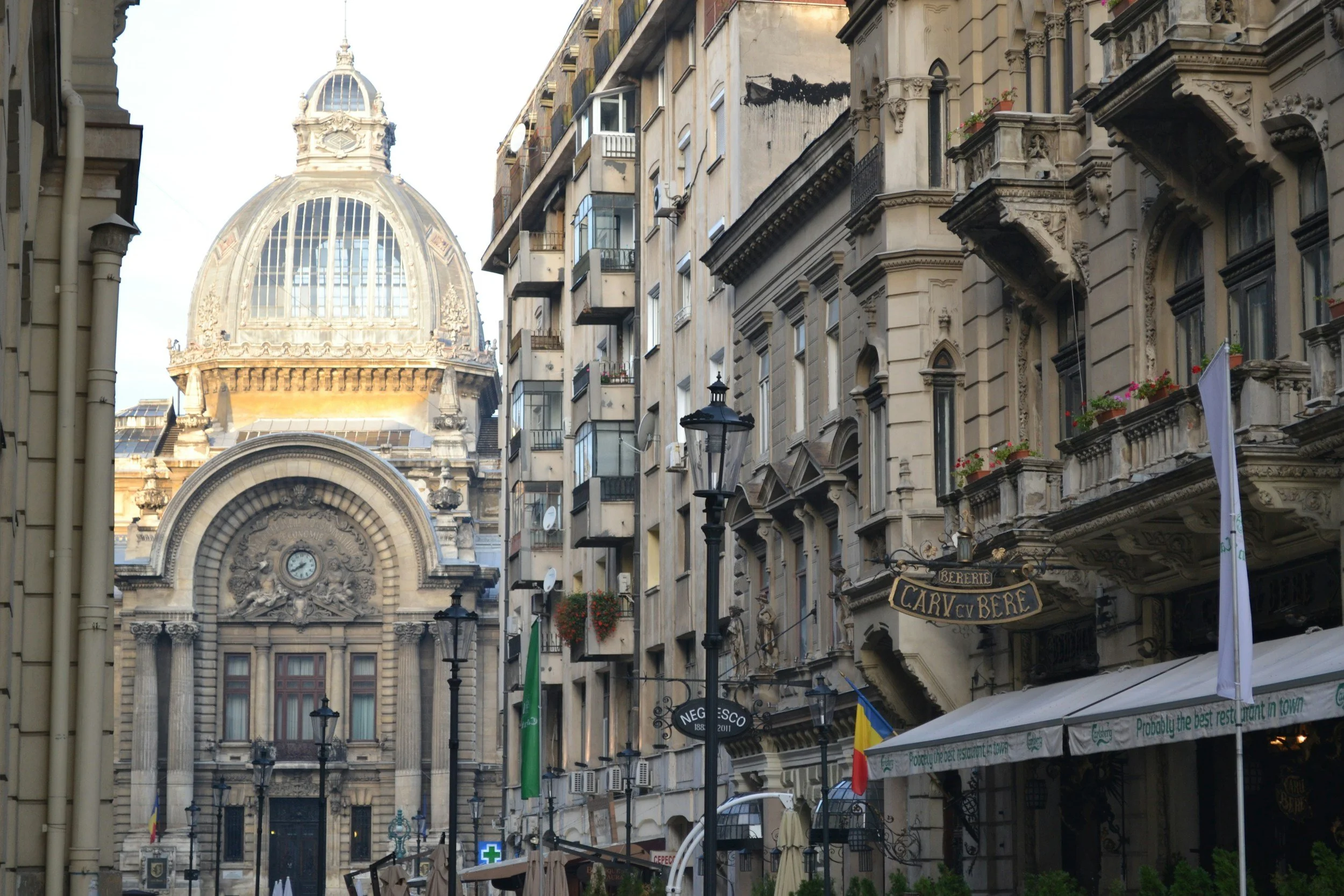 Calles estrechas con edificios históricos y una cúpula en el fondo, con señalizaciones y terrazas de cafés.