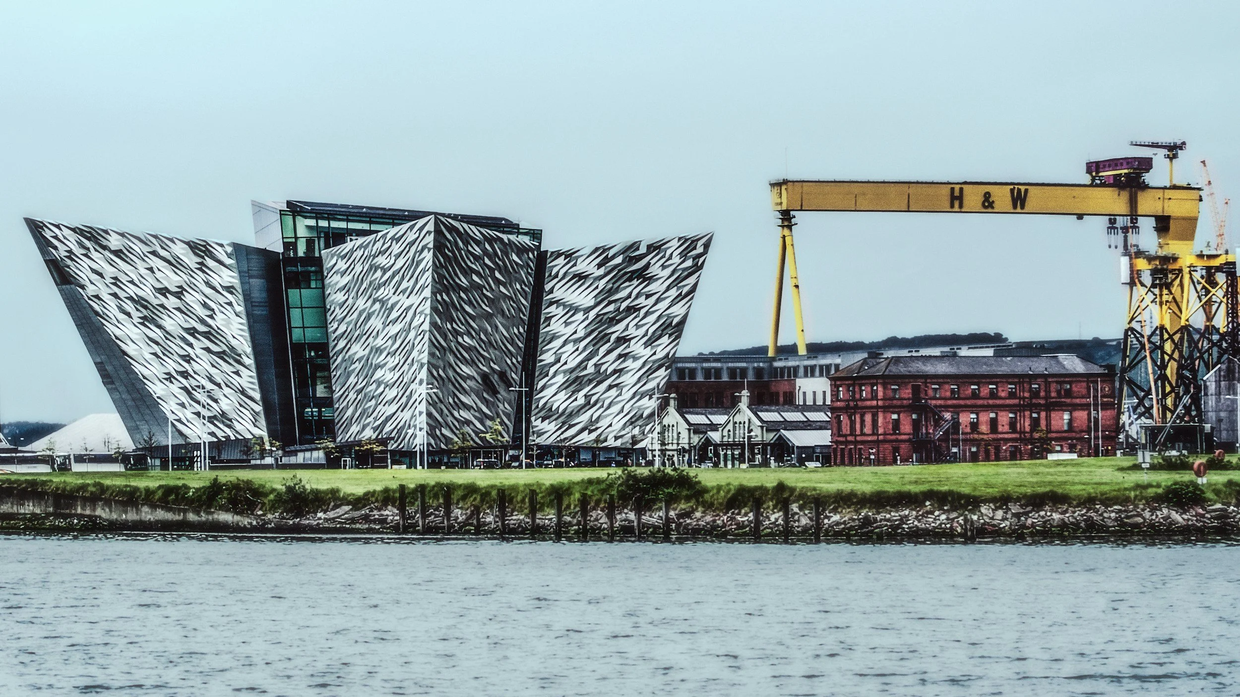 Vista del Museo de Arte de Dundee con un crisol amarillo grande y un edificio antiguo de ladrillos.