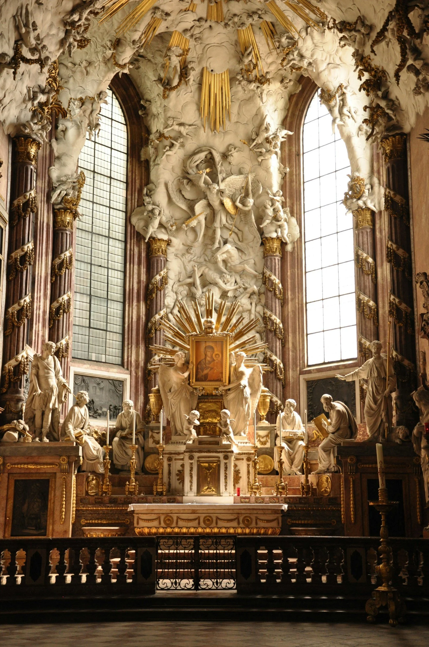 Interior decorado con esculturas de mármol, con un altar central y vitrales grandes en las ventanas.