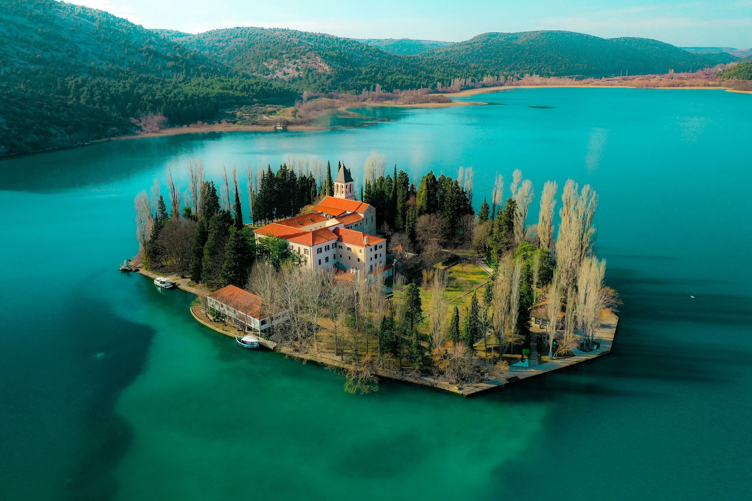 Una isla en medio de un lago rodeada de árboles y montañas.