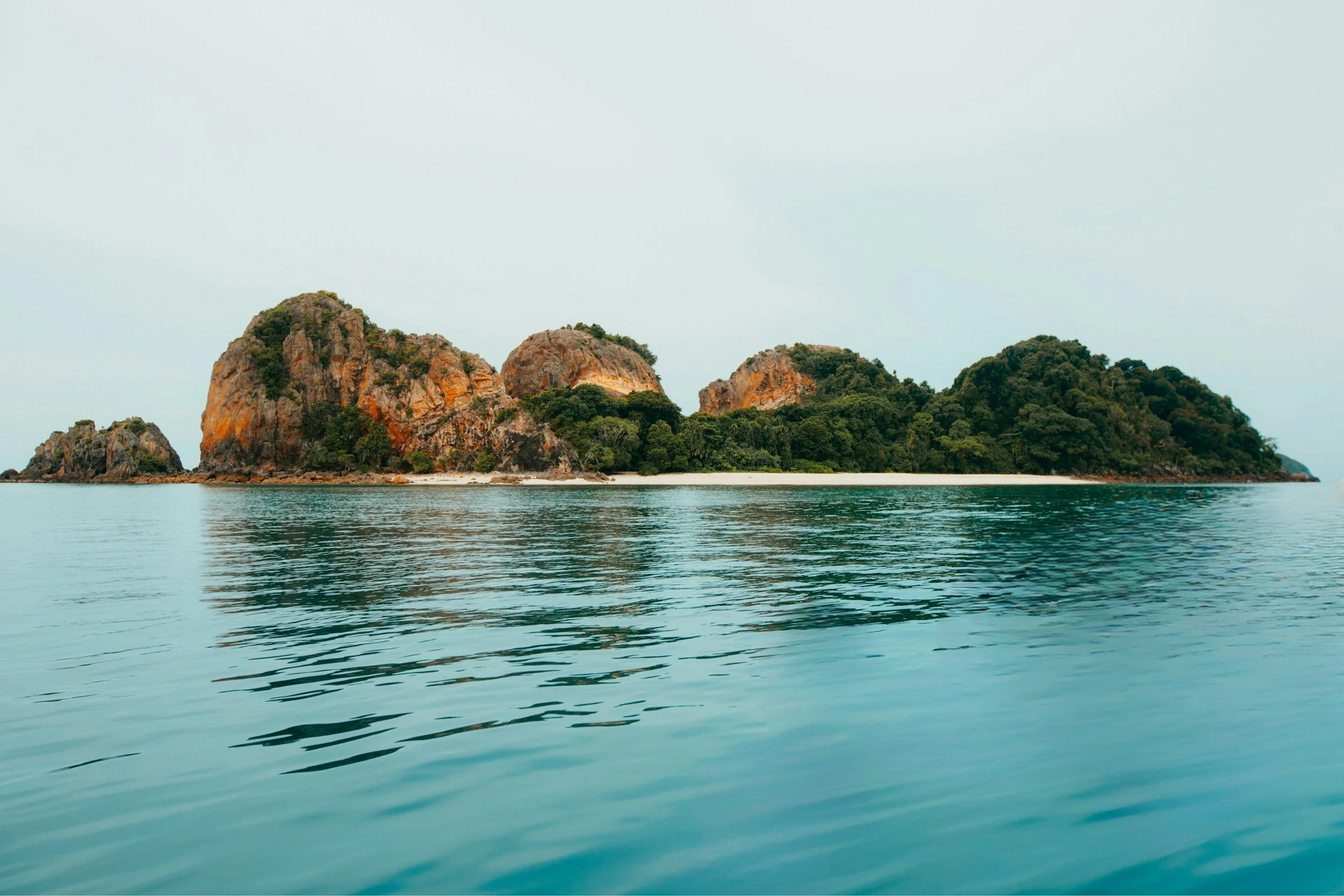 Isla con rocas y vegetación rodeada por agua calma.
