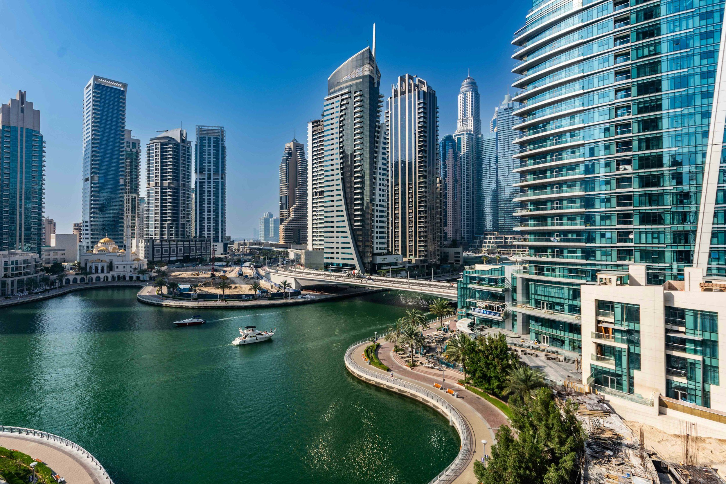 Vista de un río en un área urbana con rascacielos modernos y edificios altos, en un día soleado y despejado.