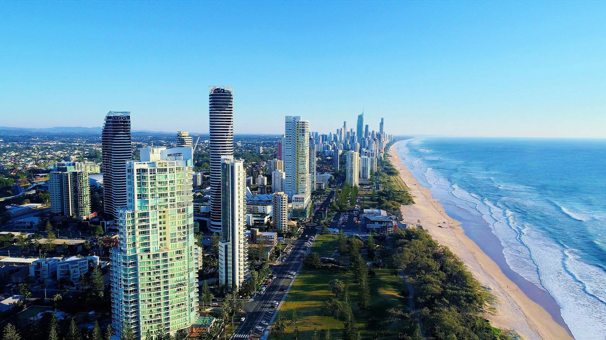 Una vista aérea de una ciudad junto a la playa con edificios altos y un mar azul claro.