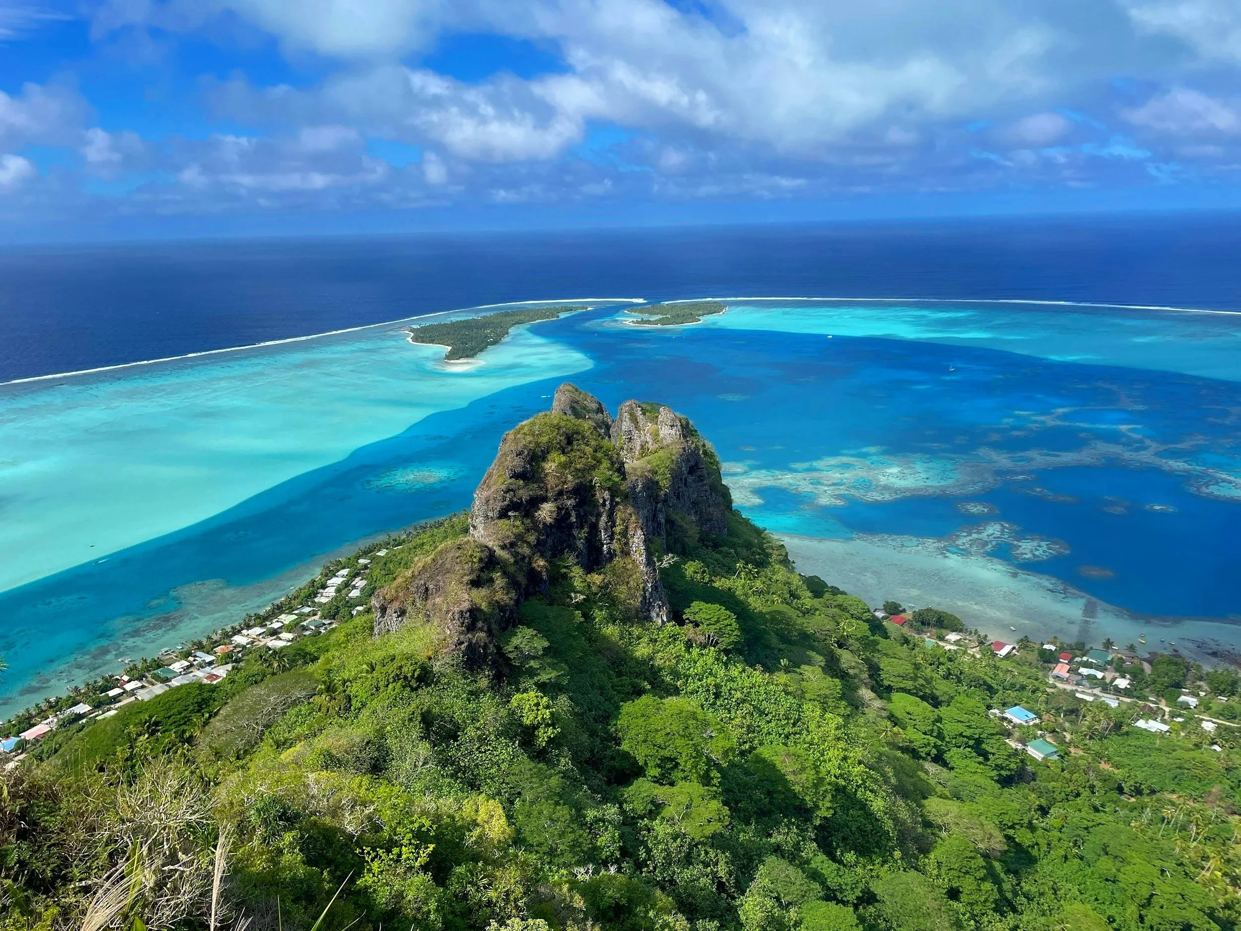 Vista aérea de una isla con arrecifes y una montaña cubierta de vegetación, rodeada por agua clara y turquoise en el Océano Atlántico.